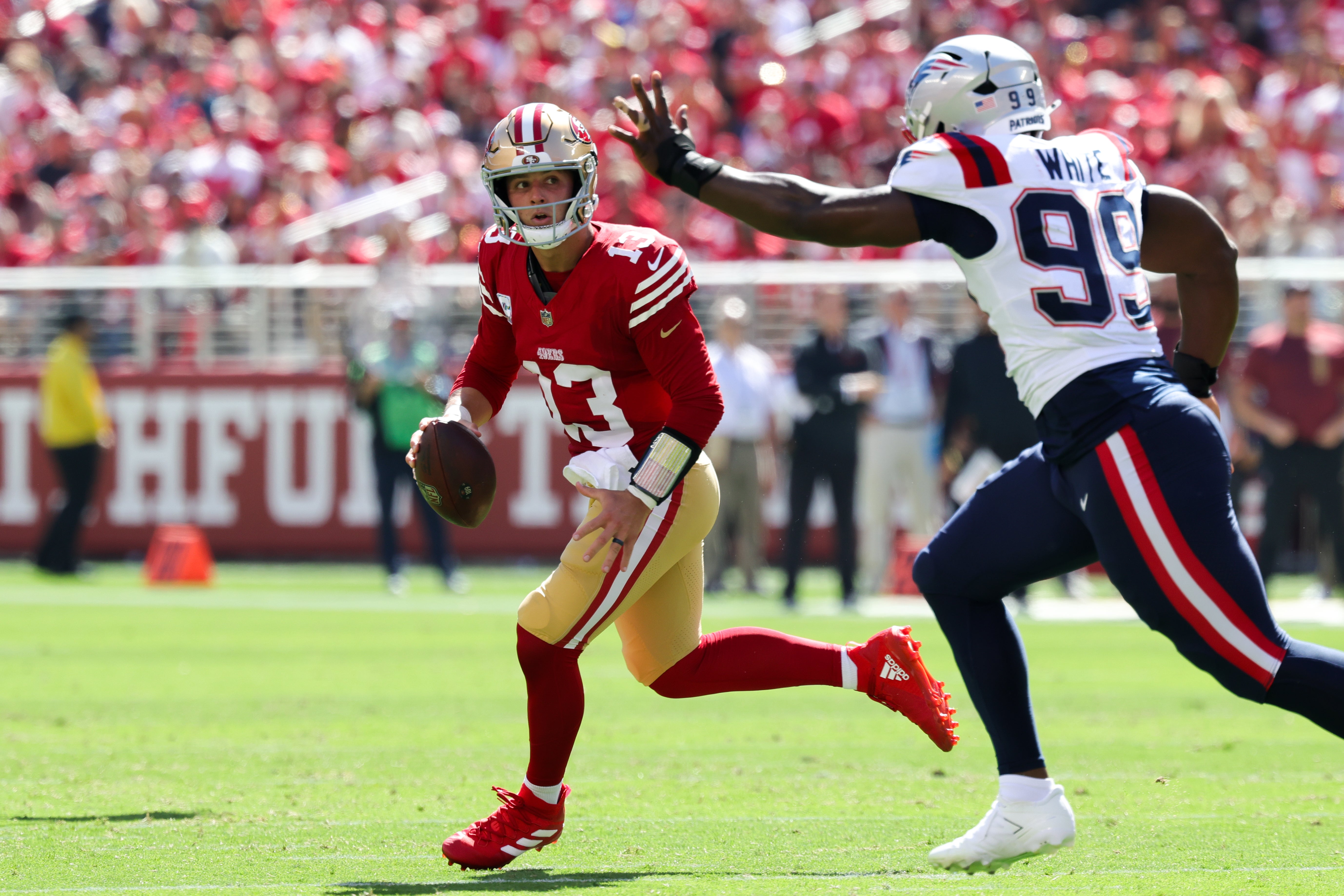 San Francisco 49ers quarterback Brock Purdy (13) runs away from New England Patriots defensive end Keion White (99) during the first quarter at Levi's Stadium.