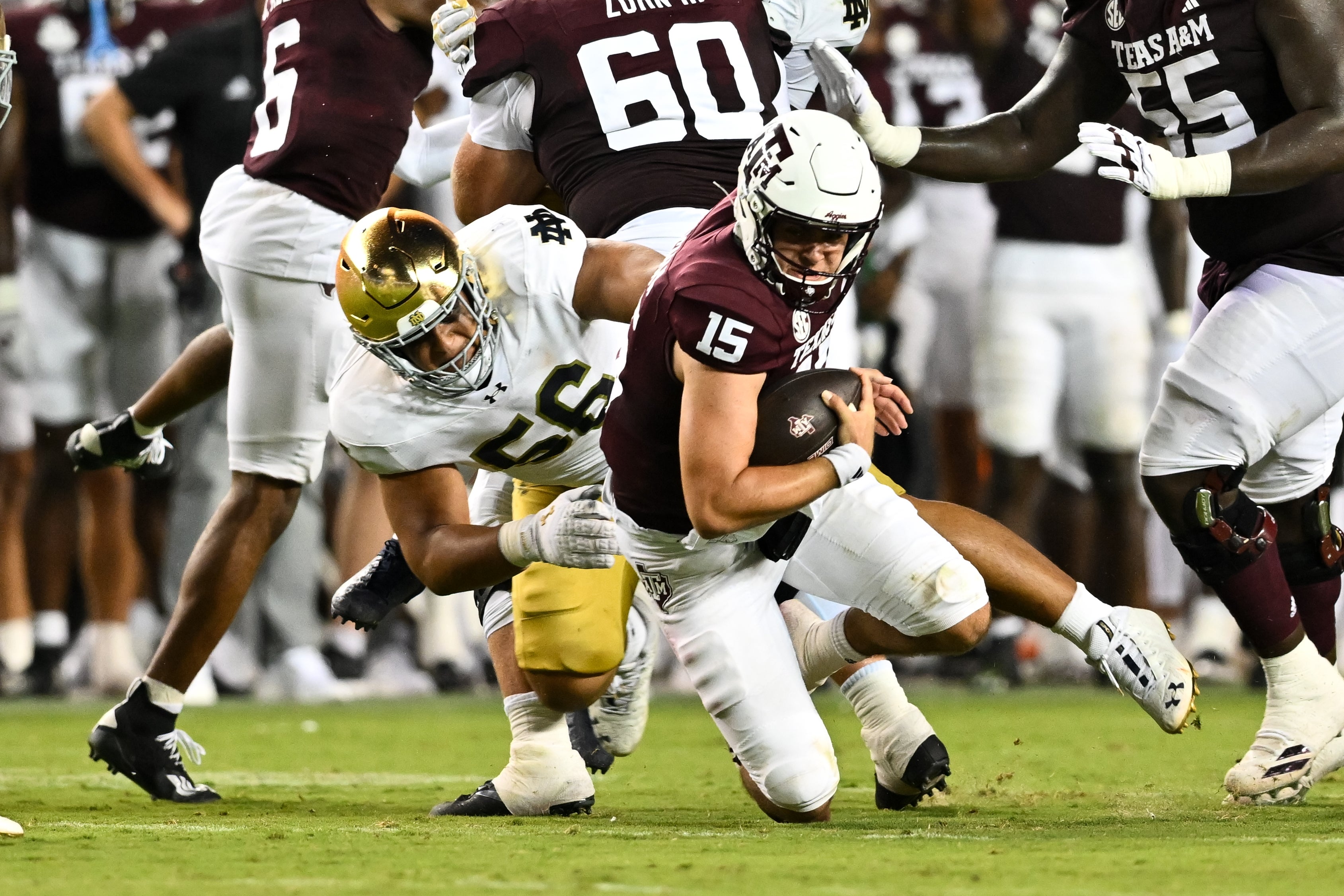 Notre Dame Fighting Irish defensive lineman Howard Cross III (56) tackles Texas A&M Aggies quarterback Conner Weigman (15) at Kyle Field.