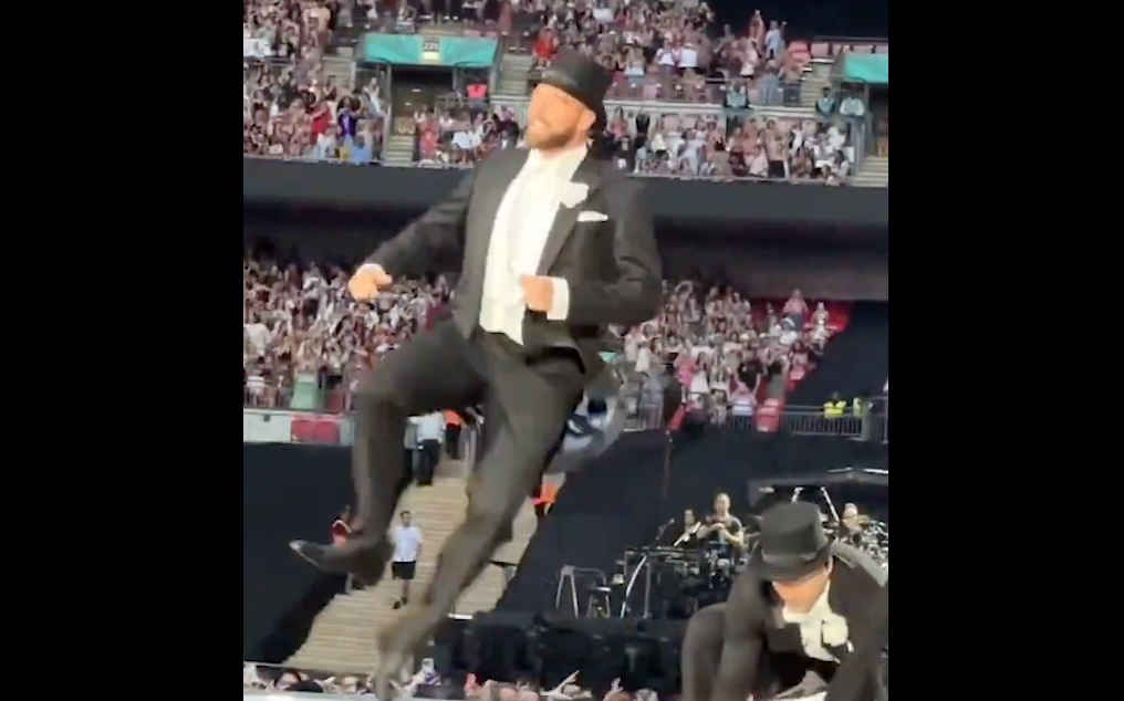 The new trailer for the New Heights podcast includes the clip of Travis Kelce on stage with Taylor Swift during her Eras Tour show at Wembley Stadium over the summer.