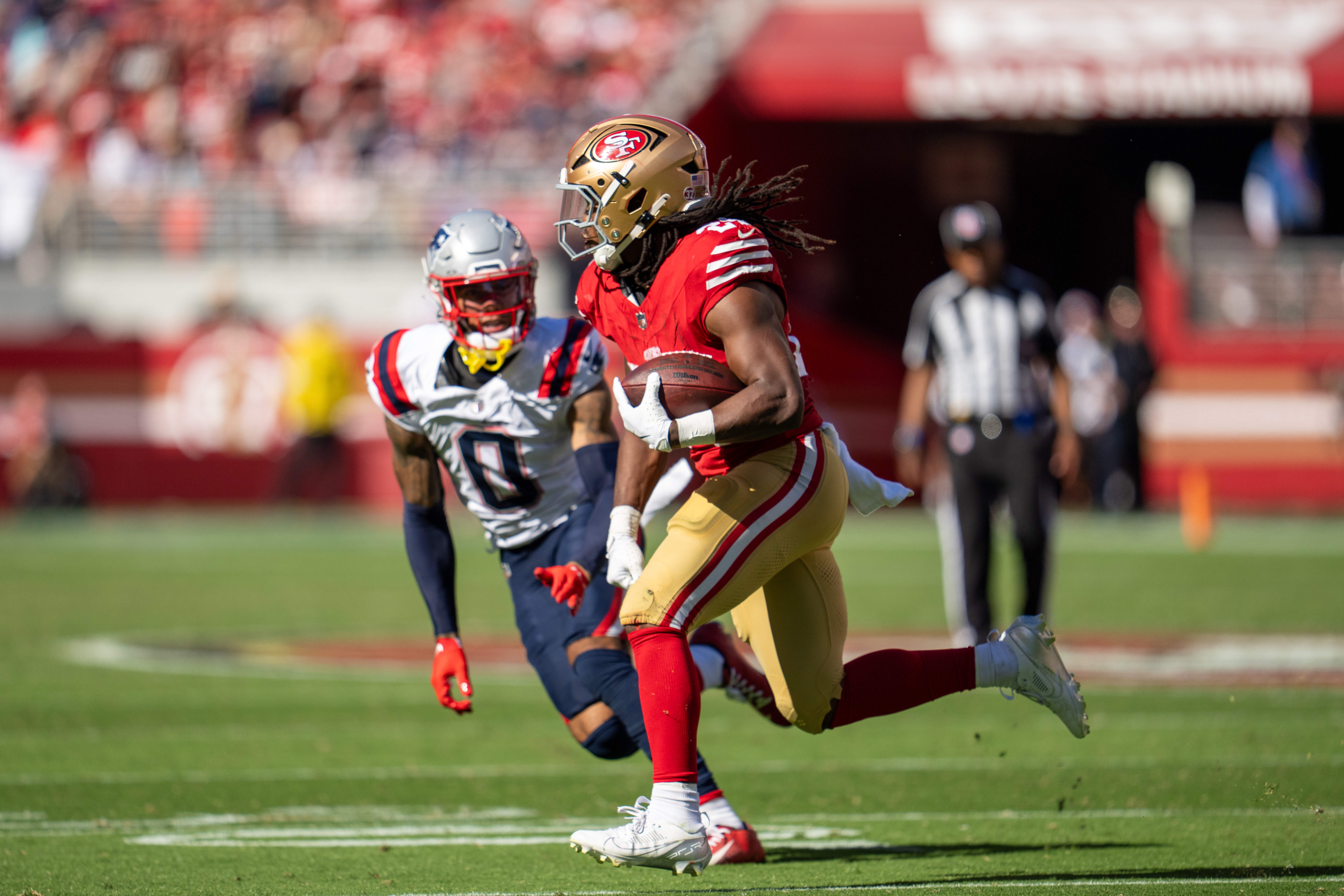 San Francisco 49ers running back Jordan Mason (24) runs for the first down against New England Patriots cornerback Christian Gonzalez (0) during the third quarter at Levi's Stadium.