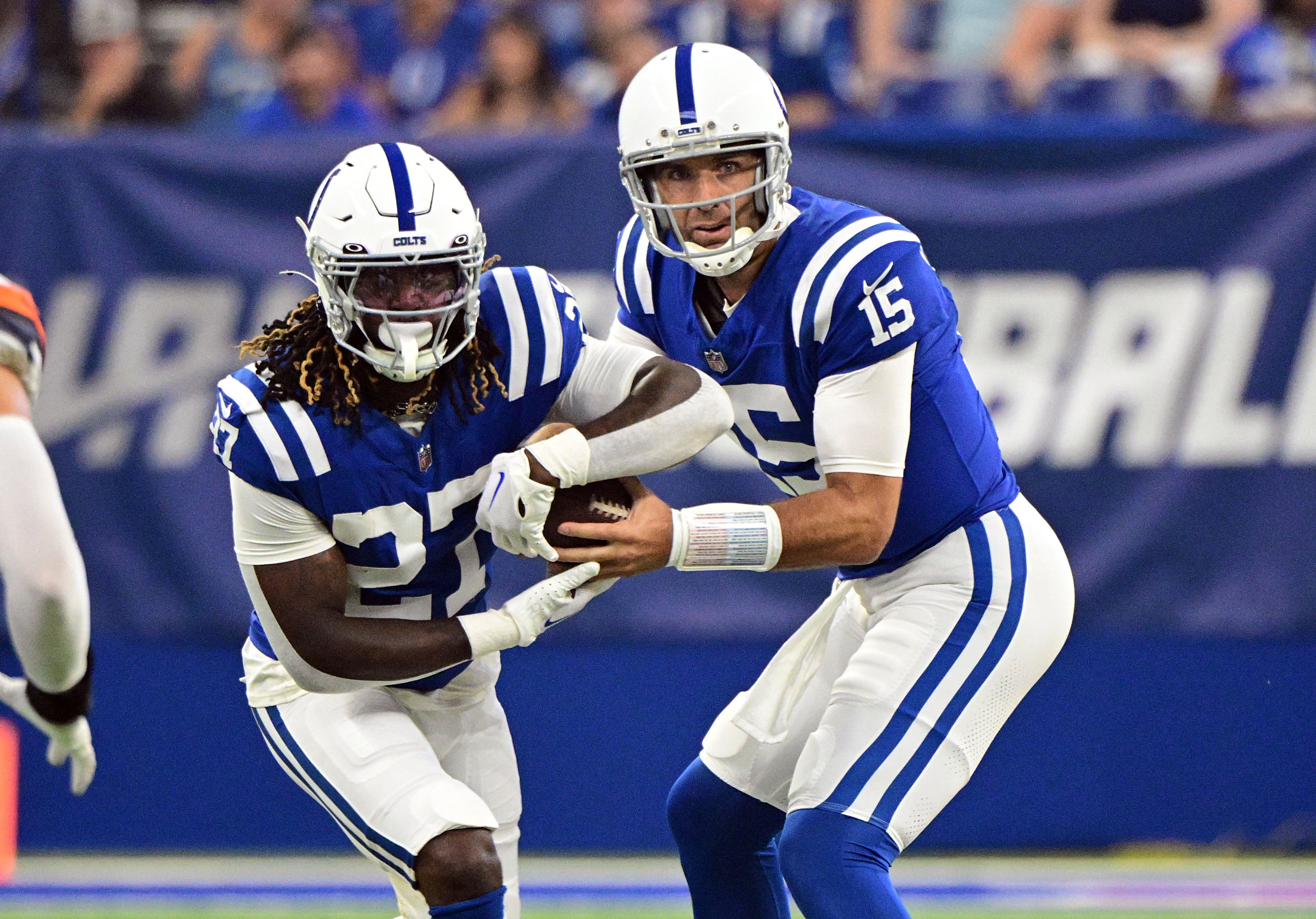 Aug 11, 2024; Indianapolis, Indiana, USA; Indianapolis Colts quarterback Joe Flacco (15) hands the ball off to Indianapolis Colts running back Trey Sermon (27) during the first quarter at Lucas Oil Stadium.