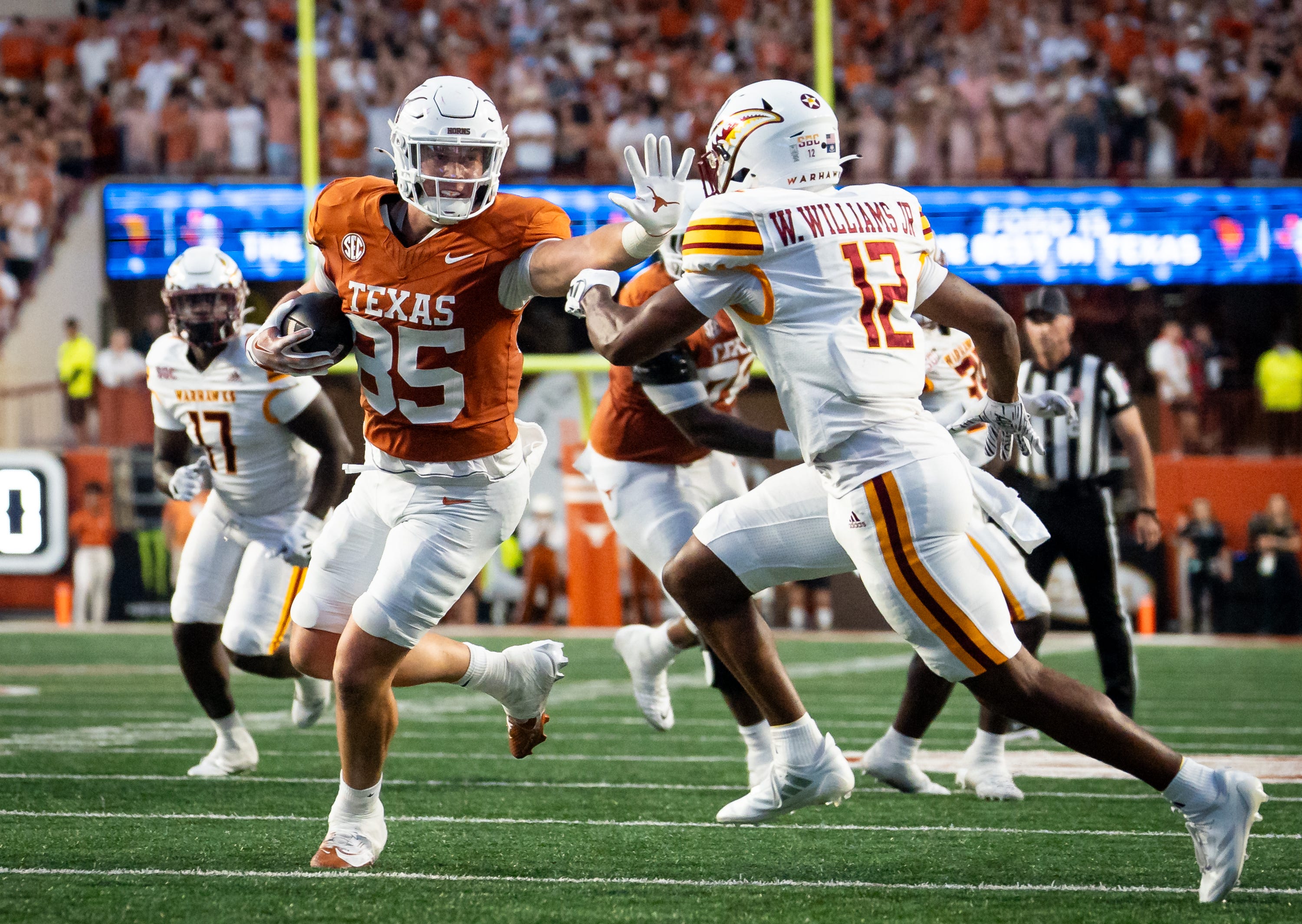 Texas Longhorns tight end Gunnar Helm (85) sticks out an arm to protect the ball as Louisiana Monroe Warhawks defensive back Wydett Williams Jr. (12) goes for the tackle in the first half of the Texas Longhorns' game against the ULM Warhawks at Darrell K Royal Texas Memorial Stadium in Austin, Sept. 21, 2024.
