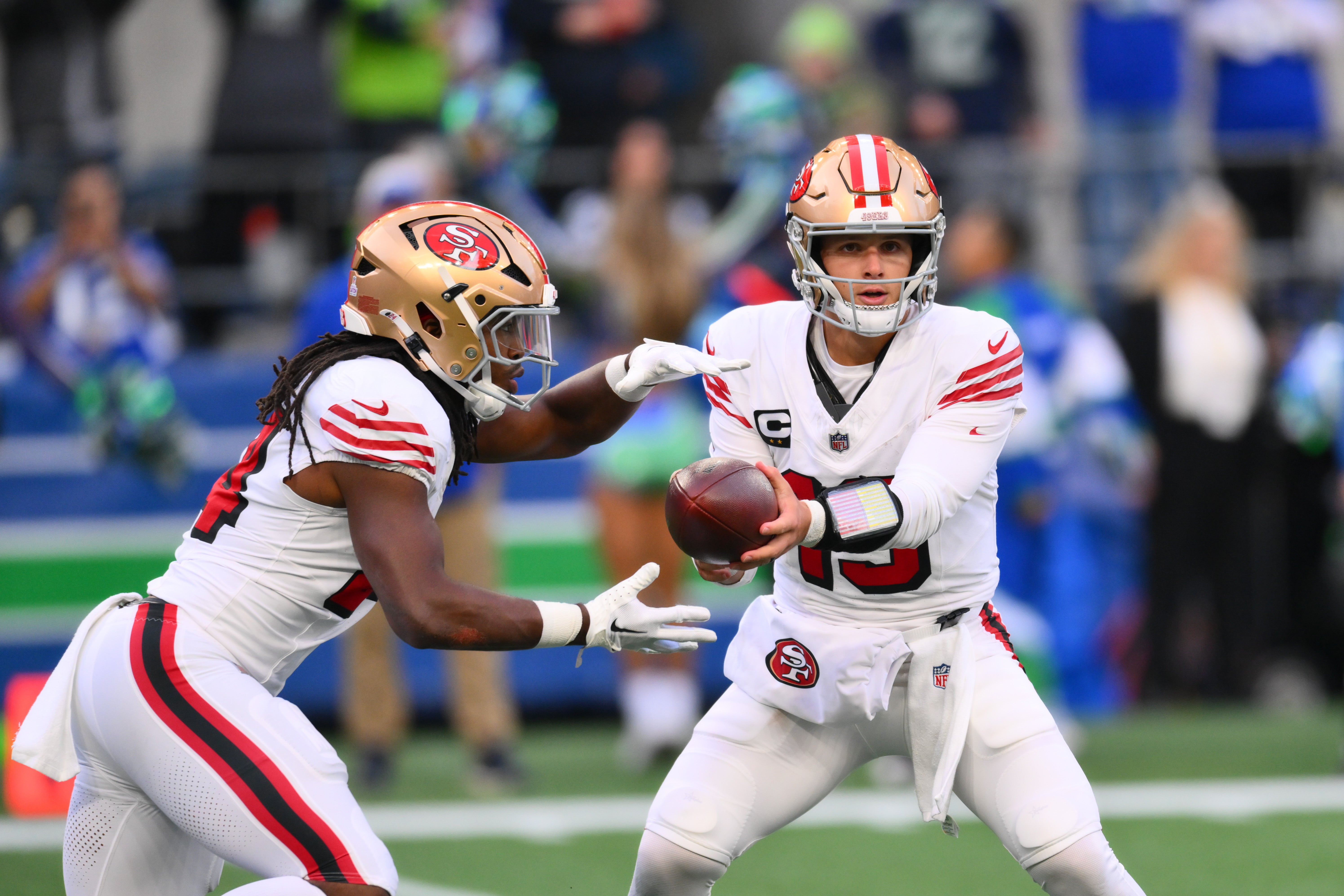 San Francisco 49ers quarterback Brock Purdy (13) hands the ball off to running back Jordan Mason (24) during the first half against the Seattle Seahawks at Lumen Field.