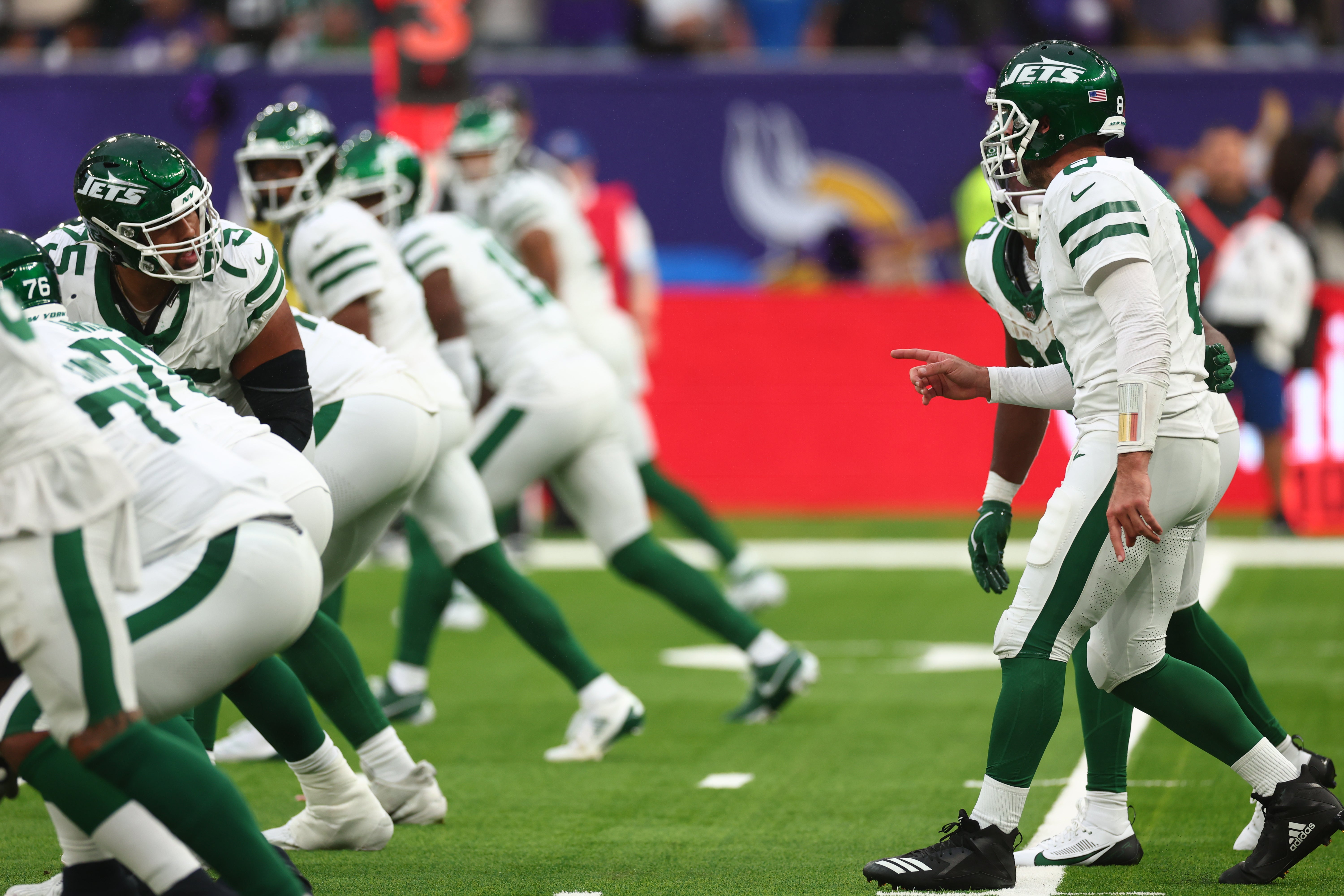 New York Jets Offensive linesman Alijah Vera-Tucker (75) checks the play Quarterback Aaron Rodgers (8) calls in the 3rd Quarter against Minnesota Vikings at Tottenham Hotspur Stadium.