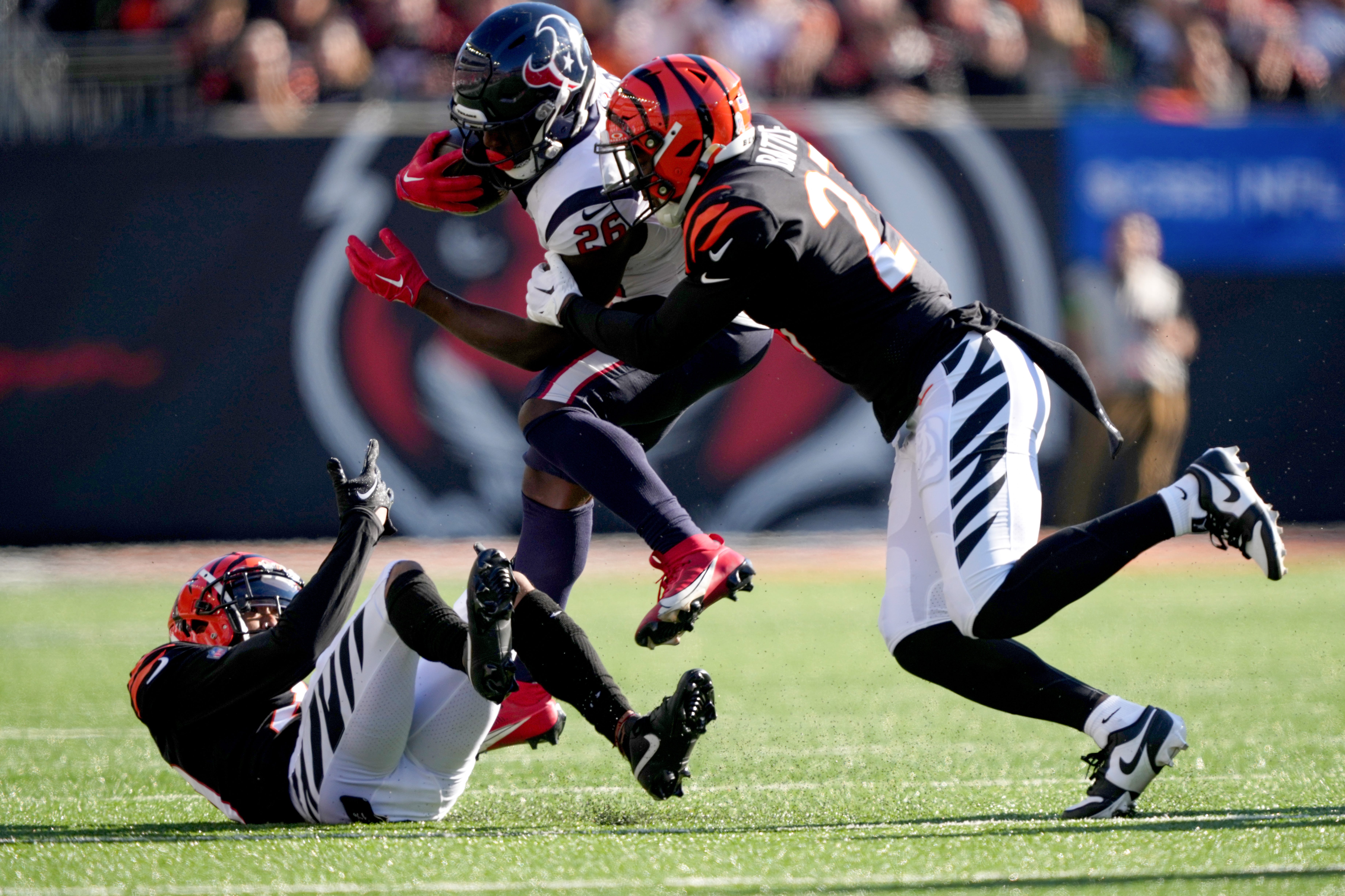 Houston Texans running back Devin Singletary (26) carries the ball as Cincinnati Bengals safety Jordan Battle (27) and Cincinnati Bengals cornerback DJ Turner II (20) defend in the second quarter of a Week 10 NFL football game between the Houston Texans and the Cincinnati Bengals, Sunday, Nov. 12, 2023, at Paycor Stadium in Cincinnati.