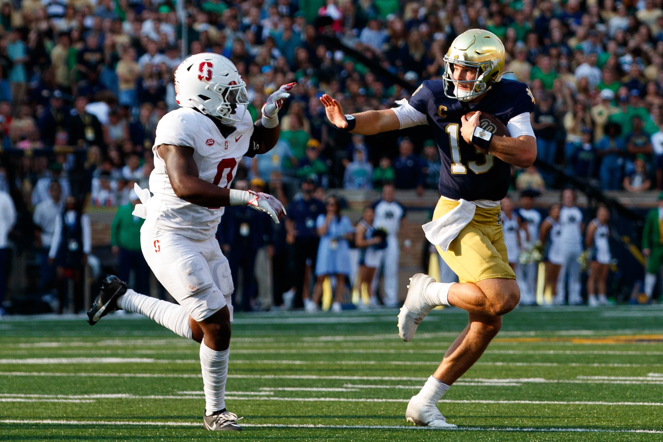 Notre Dame quarterback Riley Leonard (13) reaches out to stiff arm Stanford linebacker Gaethan Bernadel (0) during a NCAA college football game between Notre Dame and Stanford at Notre Dame Stadium on Saturday, Oct. 12, 2024, in South Bend.