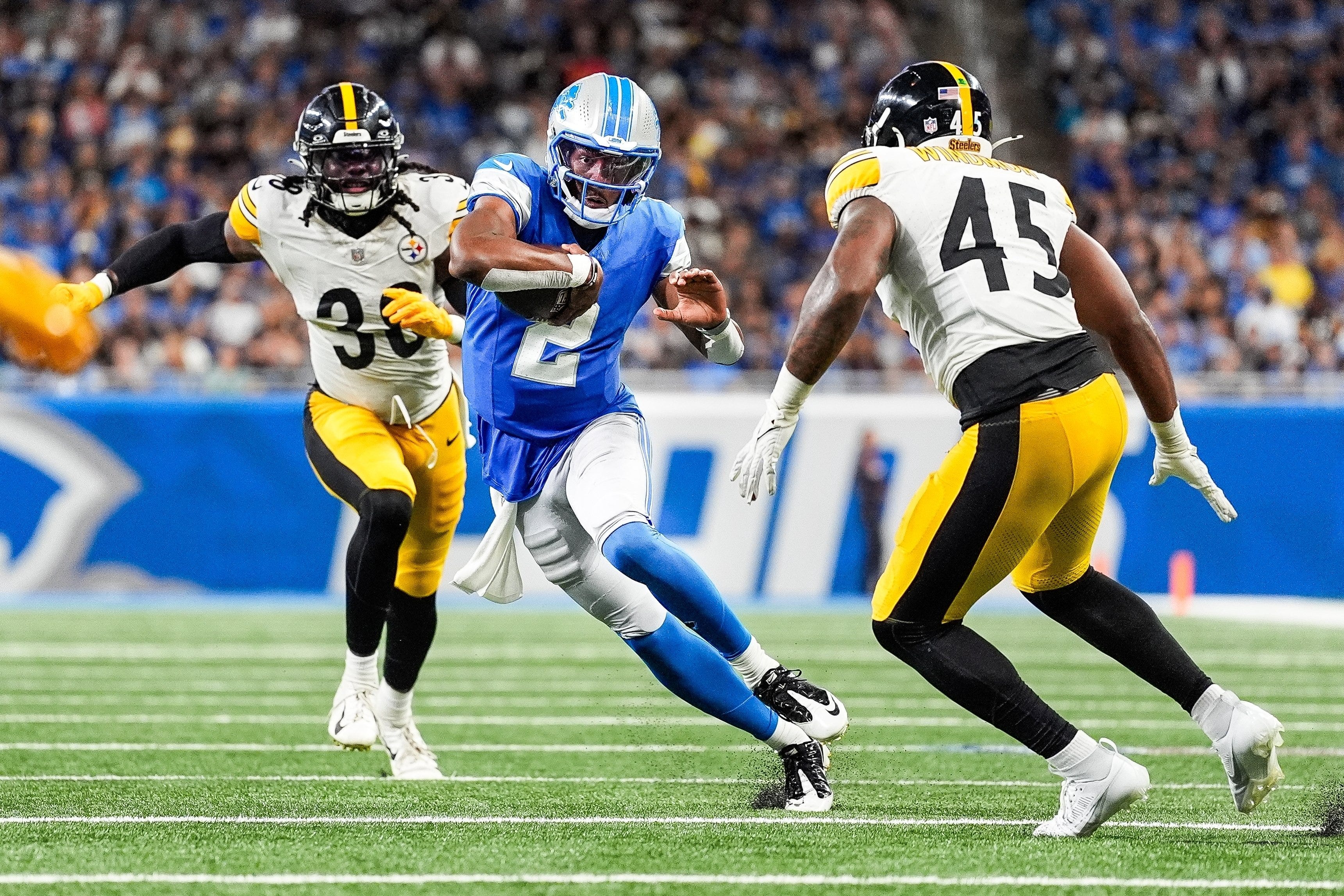 Detroit Lions quarterback Hendon Hooker (2) keeps the ball for a run against Pittsburgh Steelers running back La'Mical Perine (38), left, and linebacker Jacoby Windmon (45) during the second half of a preseason game at Ford Field in Detroit on Saturday, August 24, 2024.
