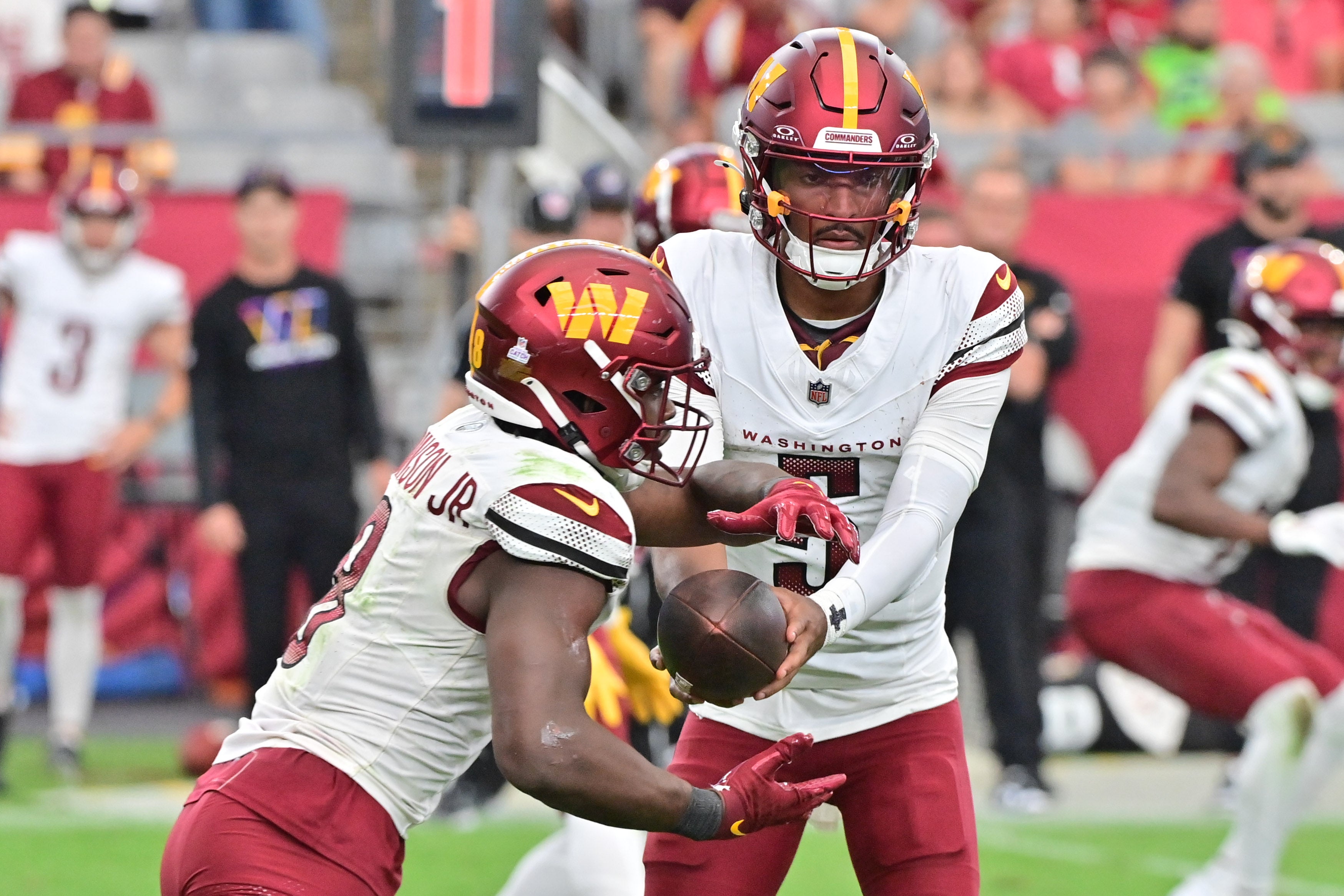 Sep 29, 2024; Glendale, Arizona, USA; Washington Commanders quarterback Jayden Daniels (5) hands off to running back Brian Robinson Jr. (8) in the second half at State Farm Stadium.