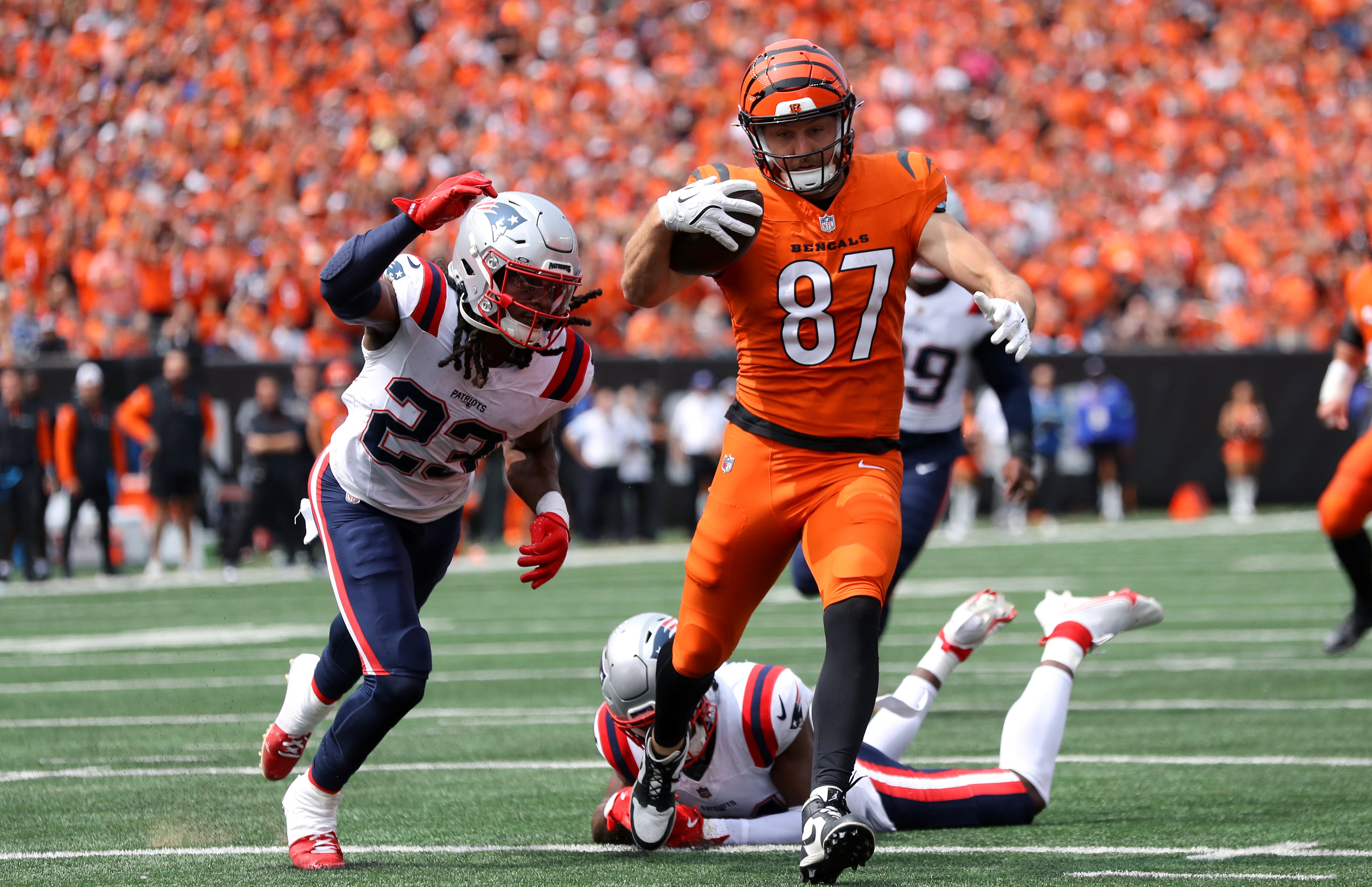 Sep 8, 2024; Cincinnati, Ohio, USA; Cincinnati Bengals tight end Tanner Hudson (87) runs to the end zone, but eventually fumbles the ball as New England Patriots safety Kyle Dugger (23) causes the turnover during the second quarter at Paycor Stadium.