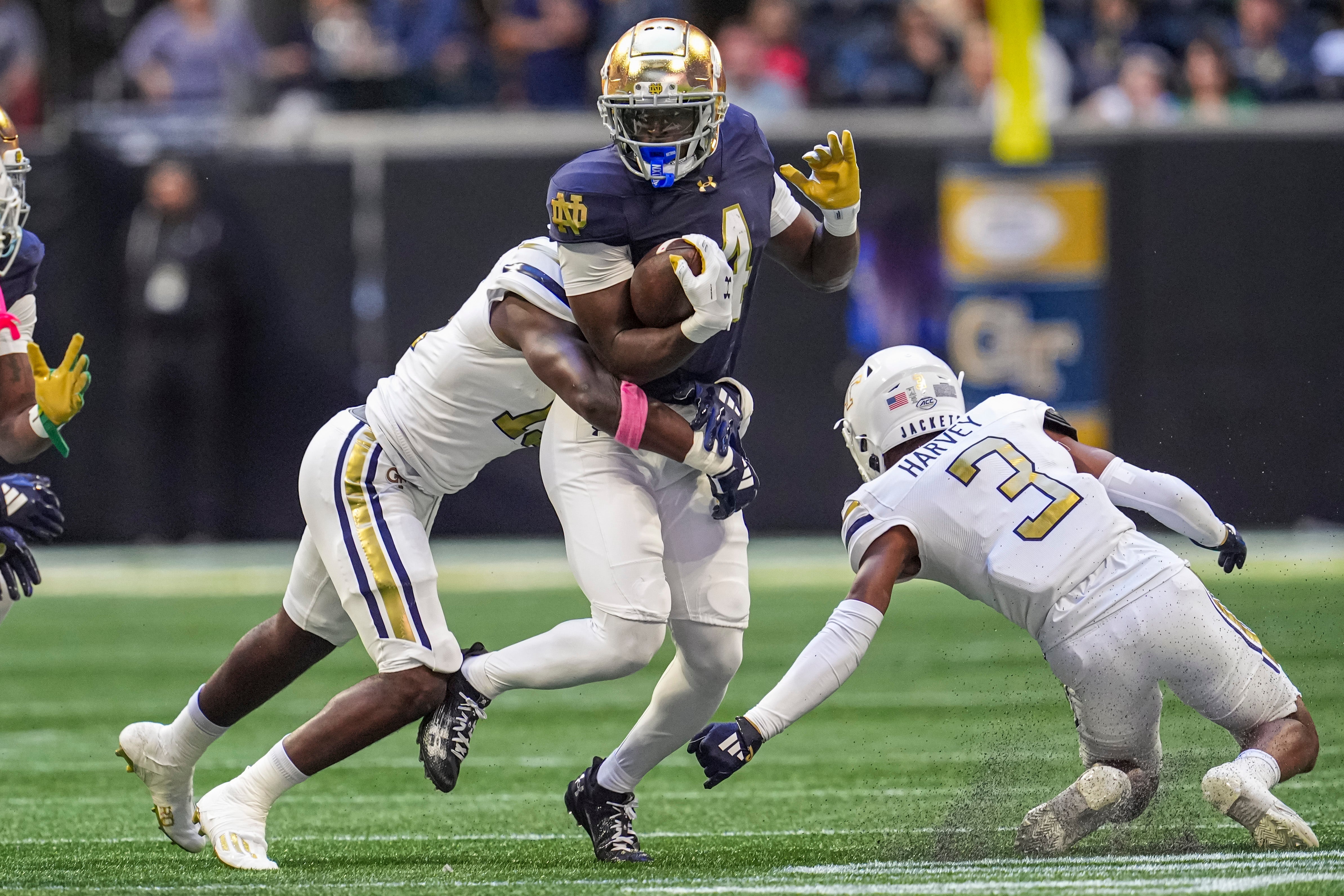 Notre Dame Fighting Irish running back Jeremiyah Love (4) runs against Georgia Tech Yellow Jackets linebacker Tah'j Butler (15) and defensive back Ahmari Harvey (3) during the first half at Mercedes-Benz Stadium.