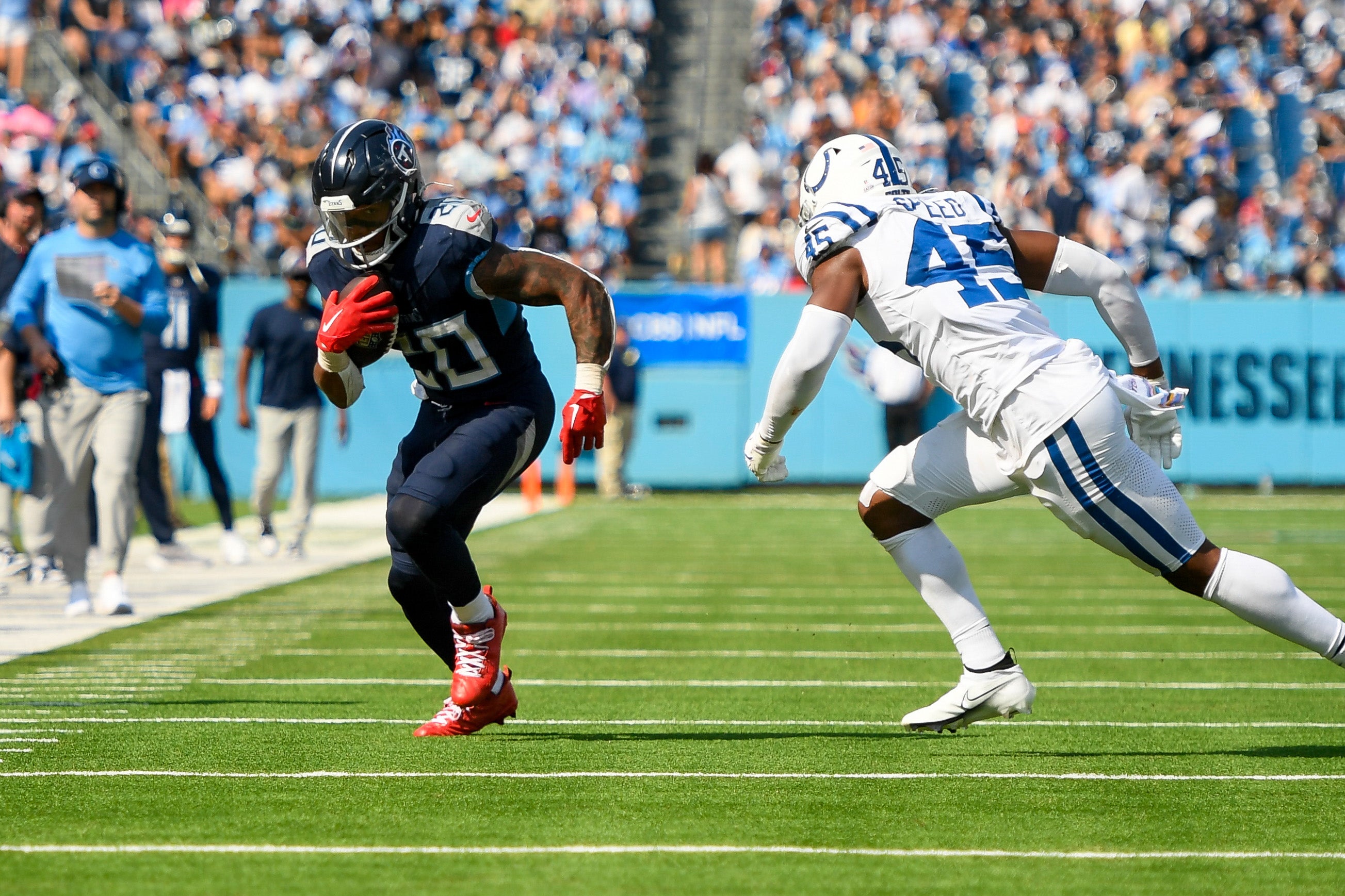 Oct 13, 2024; Nashville, Tennessee, USA; Tennessee Titans running back Tony Pollard (20) runs away from Indianapolis Colts linebacker E.J. Speed (45) during the first half at Nissan Stadium.
