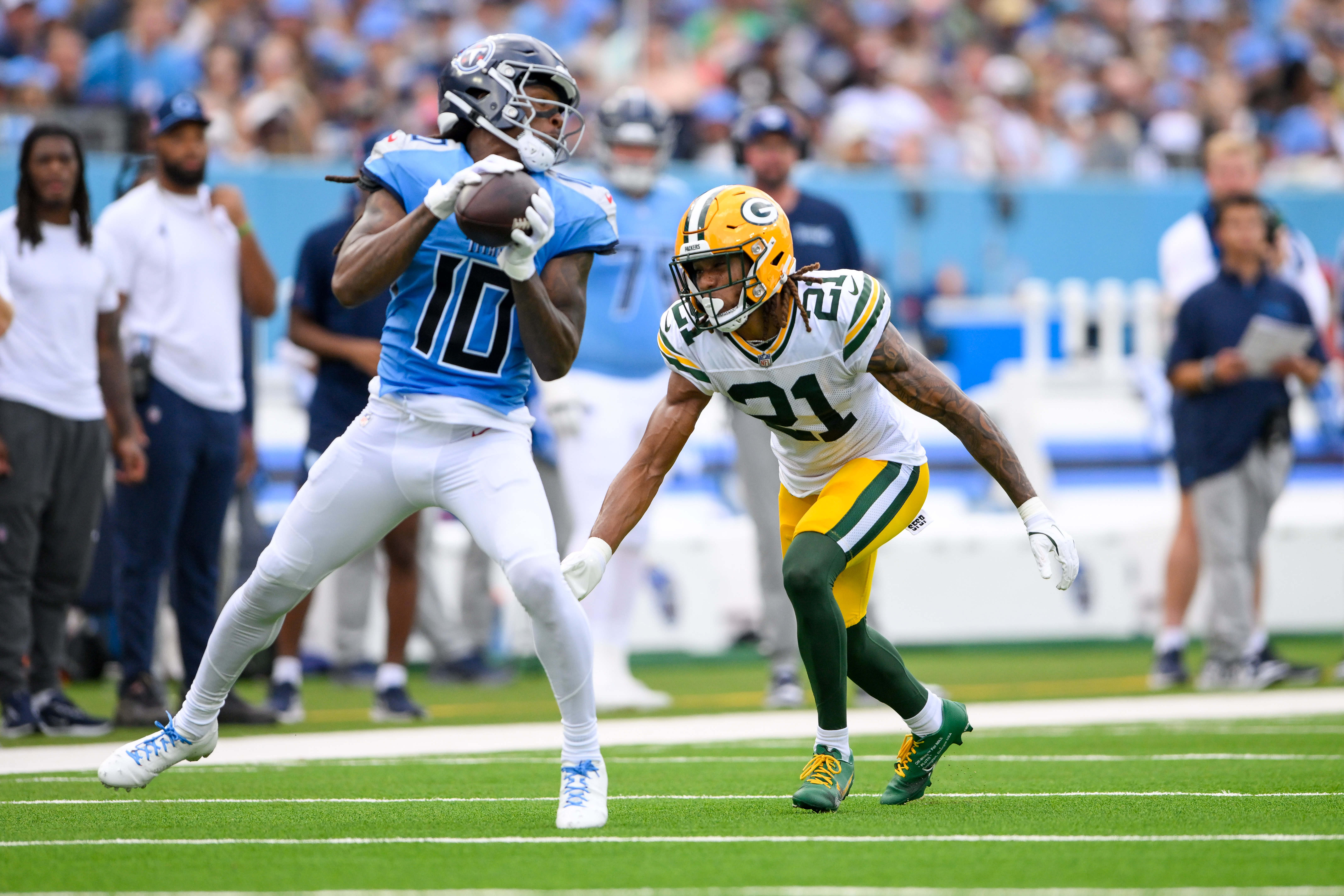 Titans WR DeAndre Hopkins makes a catch as Packers CB Eric Stokes converses.