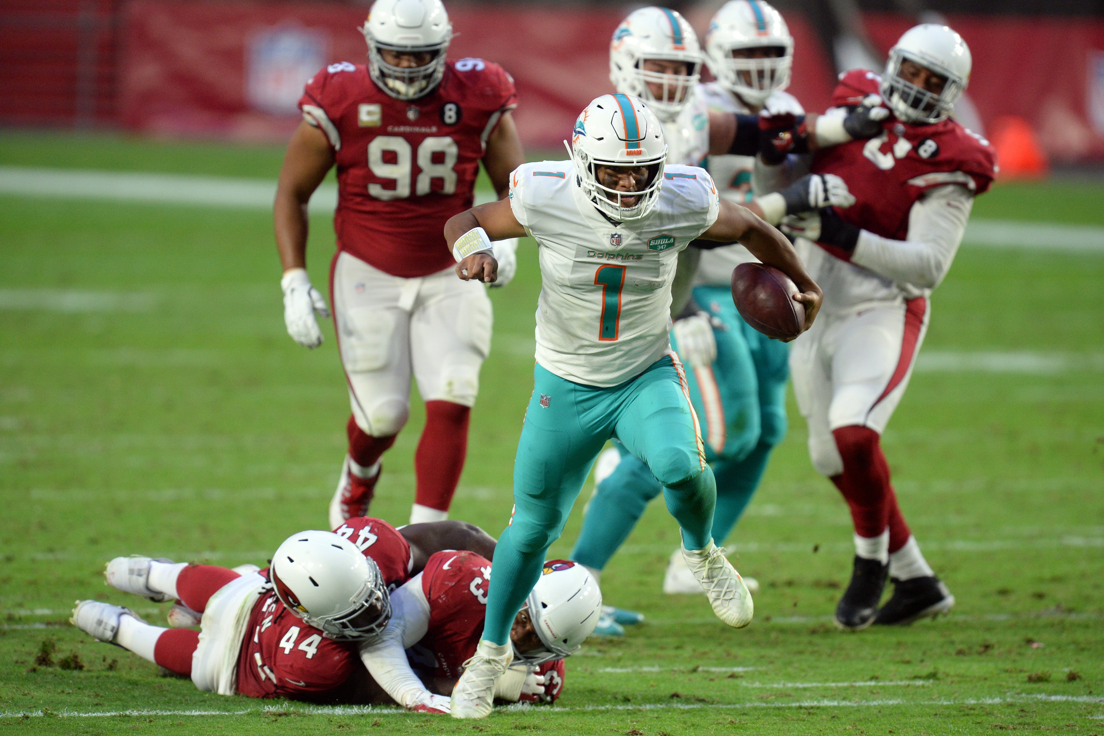 Nov 8, 2020; Glendale, Arizona, USA; Miami Dolphins quarterback Tua Tagovailoa (1) breaks the tackle of Arizona Cardinals linebacker Markus Golden (44) and Arizona Cardinals cornerback Byron Murphy (33) during the second half at State Farm Stadium.
