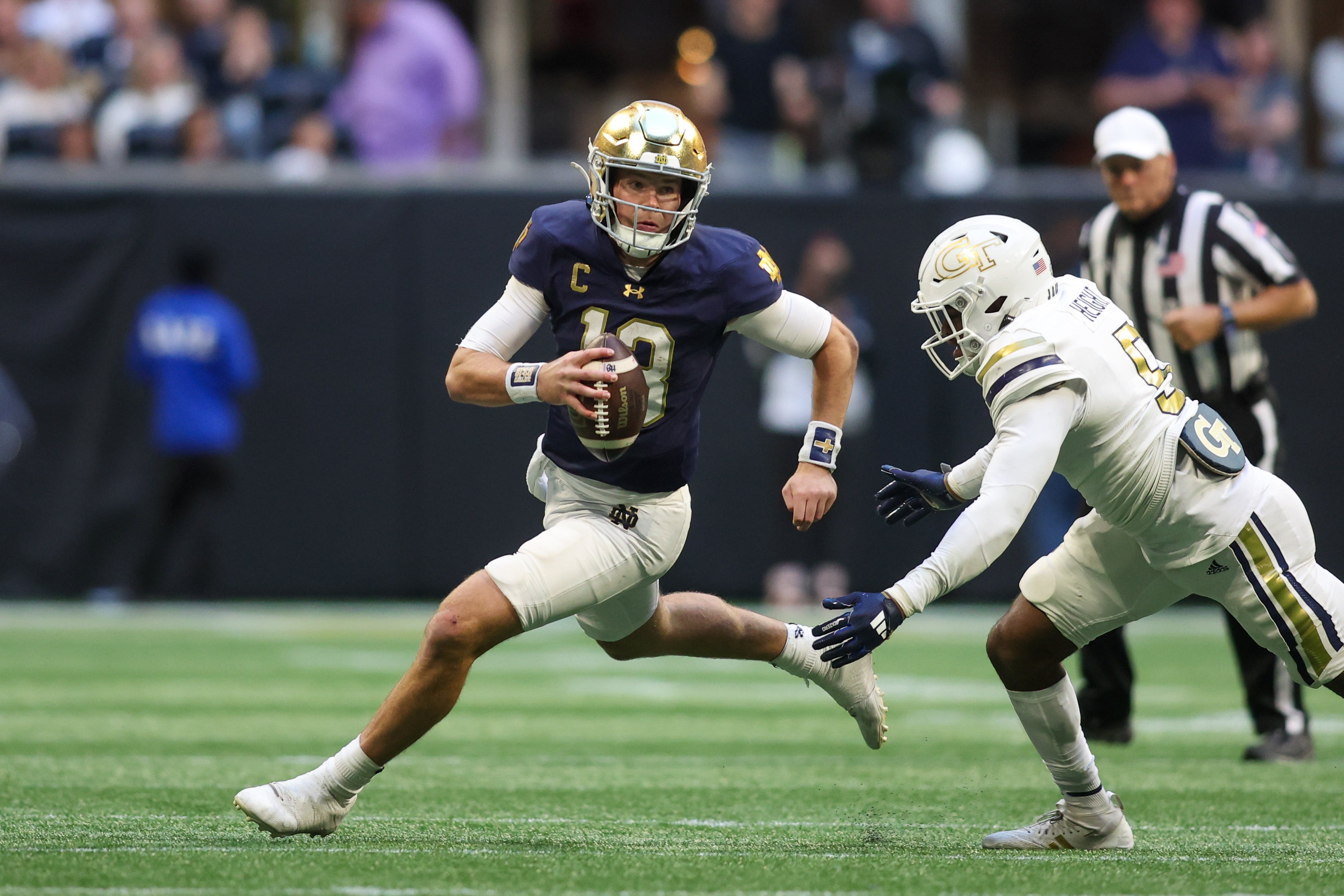 Notre Dame Fighting Irish quarterback Riley Leonard (13) scrambles past Georgia Tech Yellow Jackets defensive back Clayton Powell-Lee (5) in the fourth quarter at Mercedes-Benz Stadium.