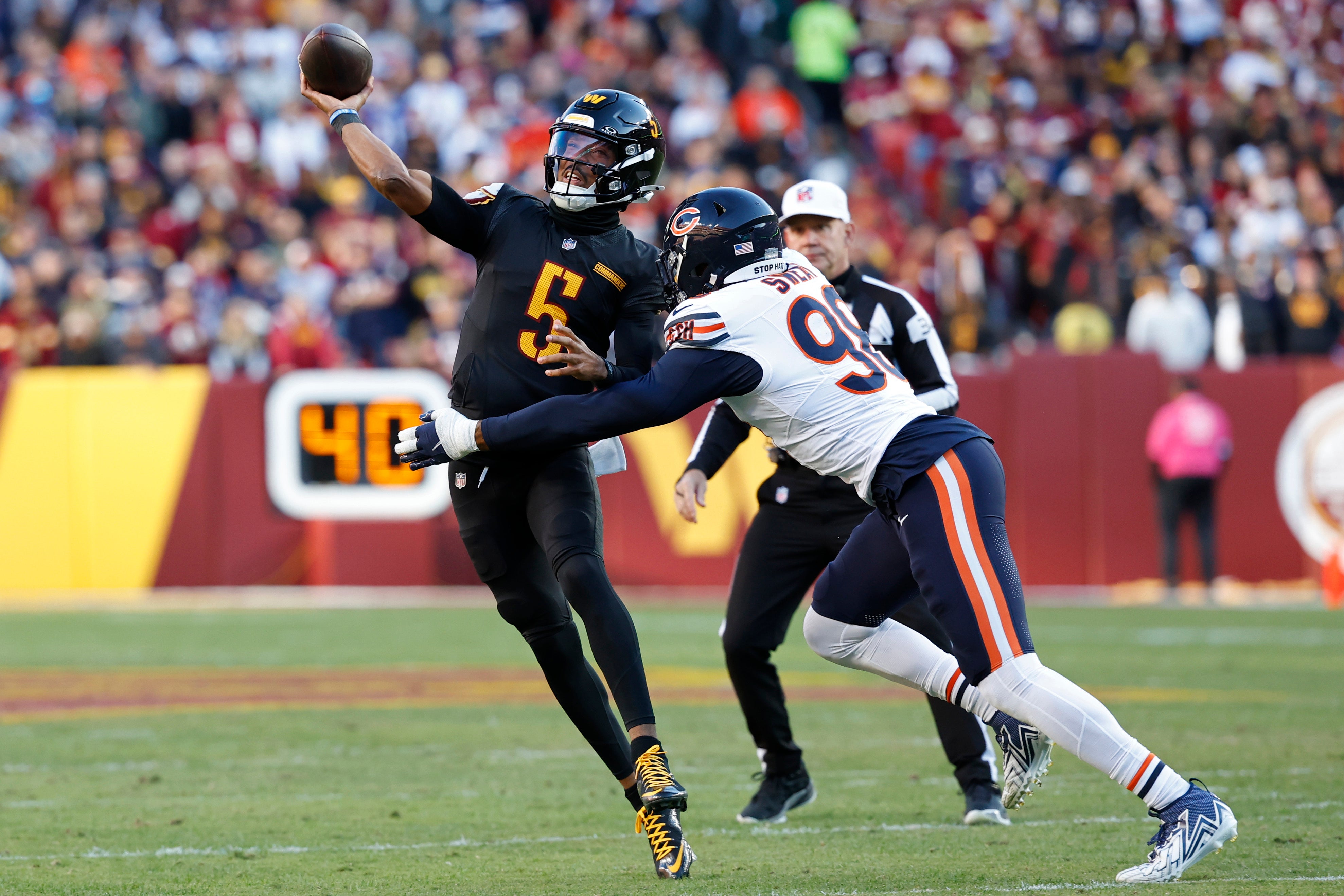 Oct 27, 2024; Landover, Maryland, USA; Washington Commanders quarterback Jayden Daniels (5) passes the ball as Chicago Bears defensive end Montez Sweat (98) chases during the first quarter at Northwest Stadium.
