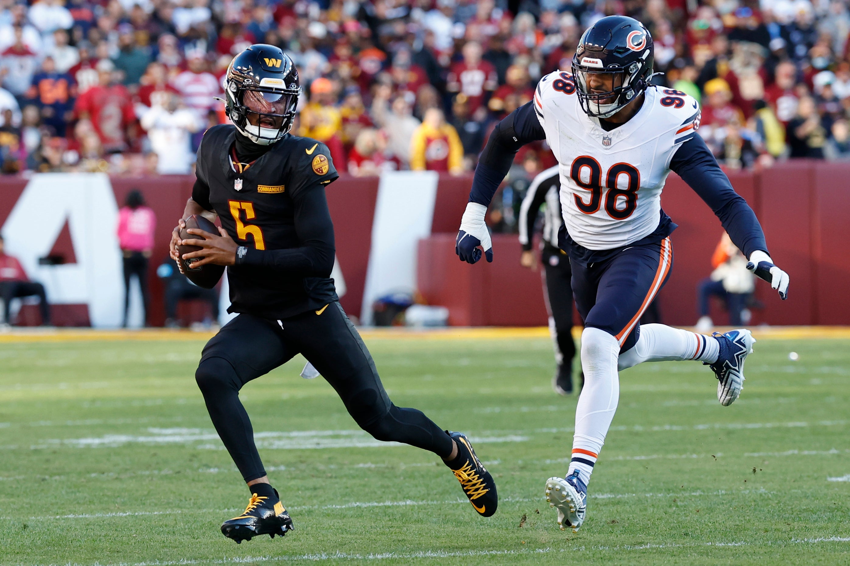 Oct 27, 2024; Landover, Maryland, USA; Washington Commanders quarterback Jayden Daniels (5) runs with the ball as Chicago Bears defensive end Montez Sweat (98)chases during the first quarter at Northwest Stadium.