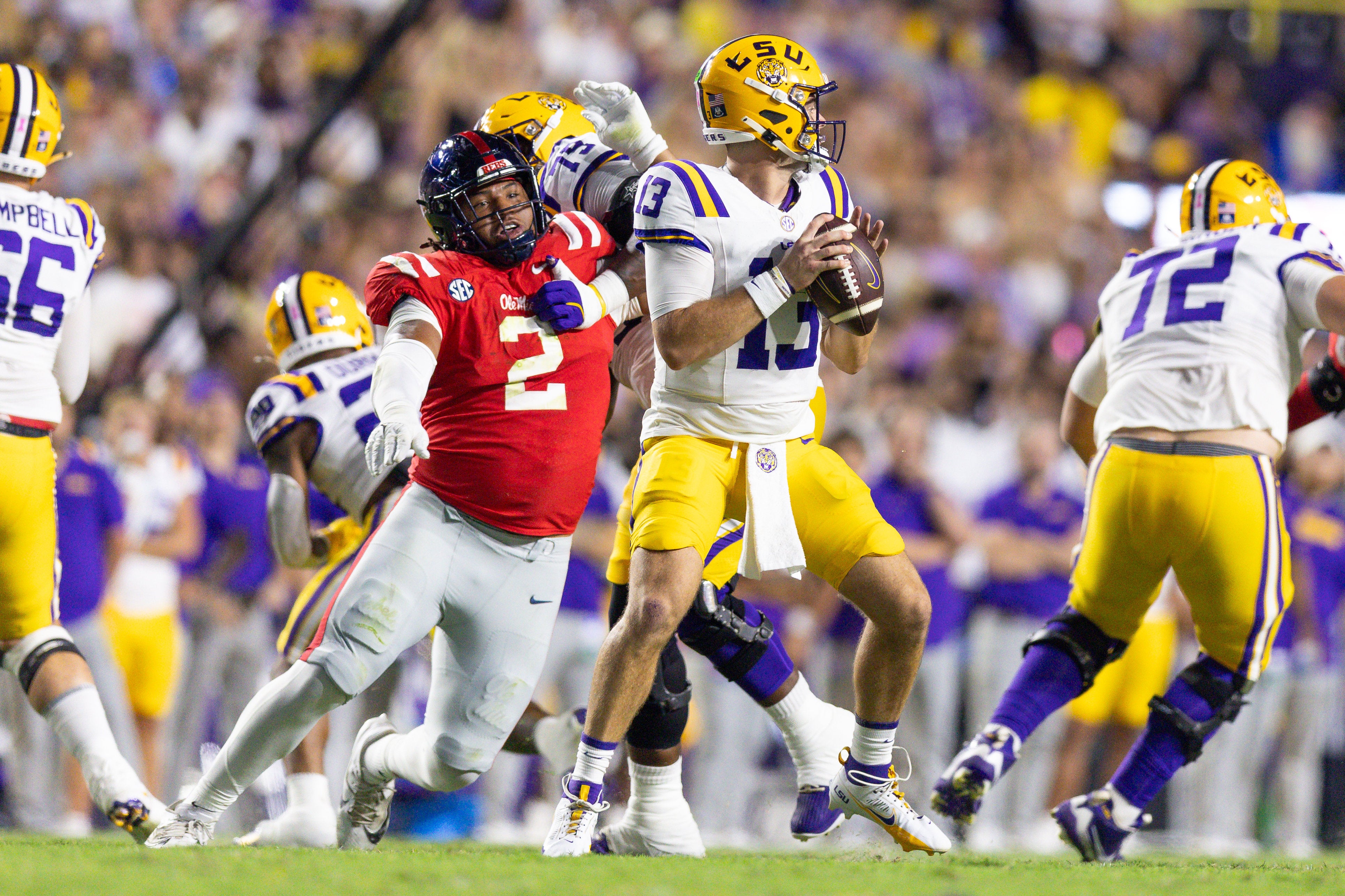 Mississippi Rebels defensive tackle Walter Nolen (2) reaches to knock the ball loose from LSU Tigers quarterback Garrett Nussmeier (13) during the first half at Tiger Stadium.