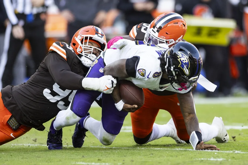 Cleveland Browns defensive end Za'Darius Smith (99) and linebacker Winston Reid (59) sack Baltimore Ravens quarterback Lamar Jackson (8) during the fourth quarter at Huntington Bank Field.