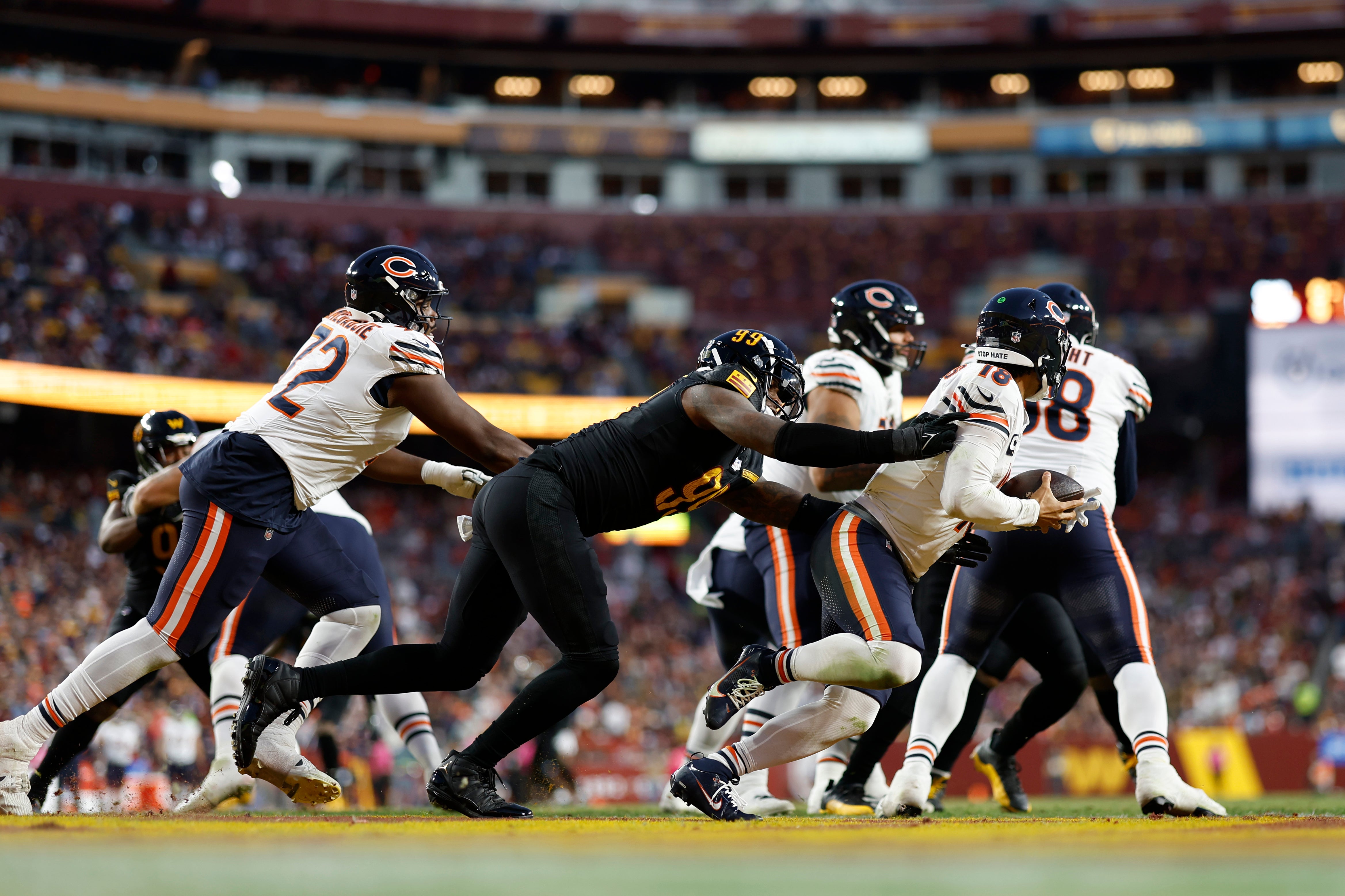 Oct 27, 2024; Landover, Maryland, USA; Chicago Bears quarterback Caleb Williams (18) scrambles from Washington Commanders defensive end Clelin Ferrell (99) during the third quarter at Northwest Stadium.