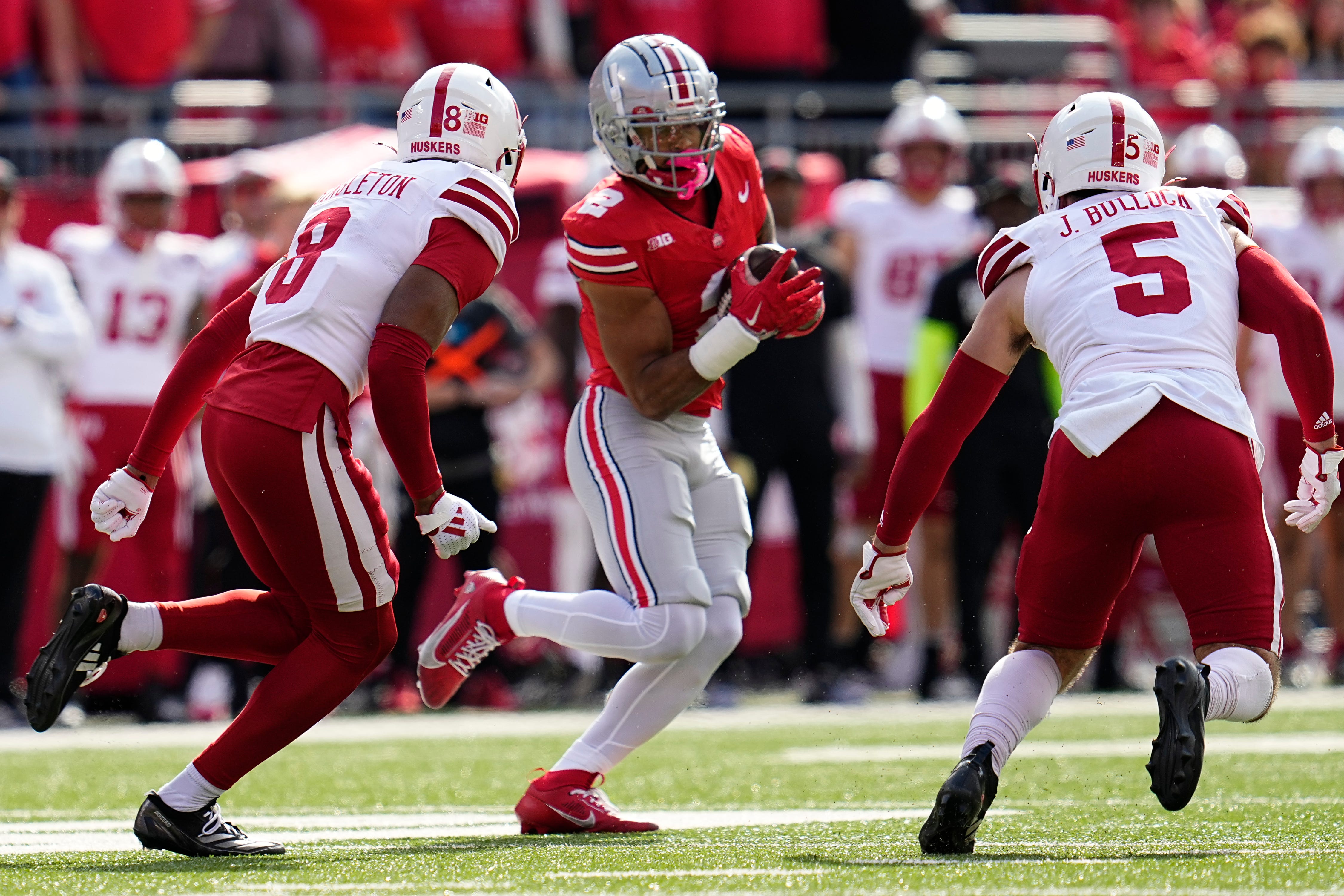 Ohio State Buckeyes wide receiver Emeka Egbuka (2) runs between Nebraska Cornhuskers defensive back DeShon Singleton (8) and linebacker John Bullock (5) after making a catch during the first half of the NCAA football game at Ohio Stadium in Columbus on Saturday, Oct. 26, 2024.