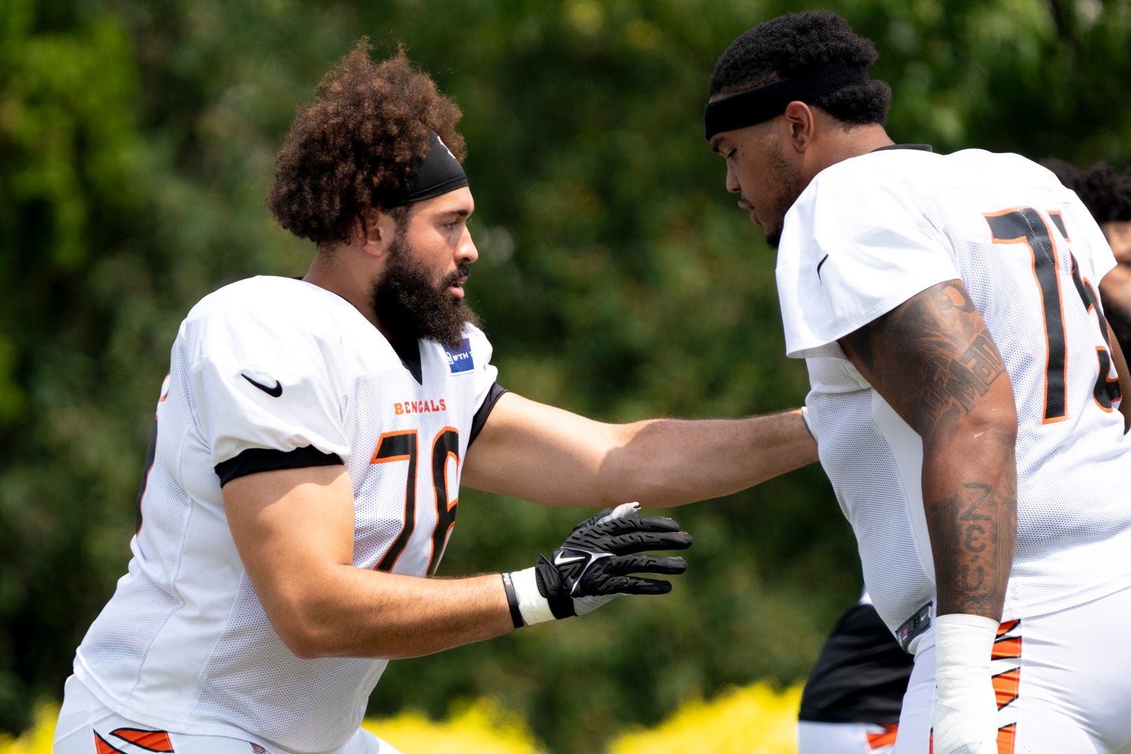 Cincinnati Bengals offensive tackle Devin Cochran (76) and Cincinnati Bengals offensive tackle Orlando Brown Jr. (75) perform a offensive line drill at Cincinnati Bengals training camp on the Kettering Health Practice Fields in Cincinnati on Sunday, Aug. 4, 2024.