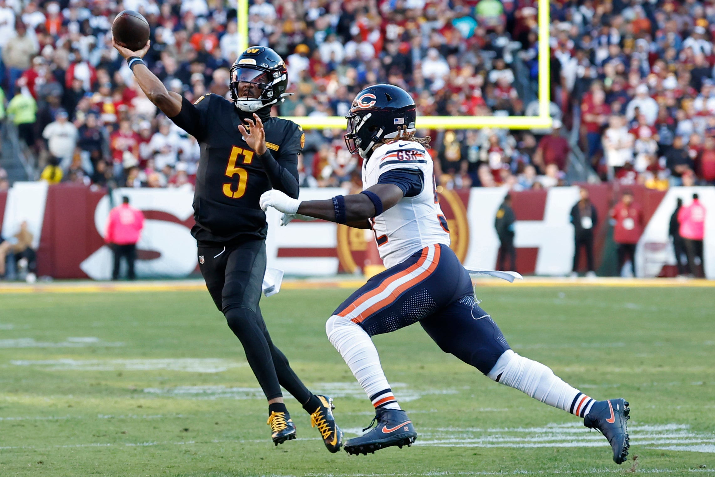 Oct 27, 2024; Landover, Maryland, USA; Washington Commanders quarterback Jayden Daniels (5) passes the ball as Chicago Bears defensive end Darrell Taylor (52) chases during the first quarter at Northwest Stadium.
