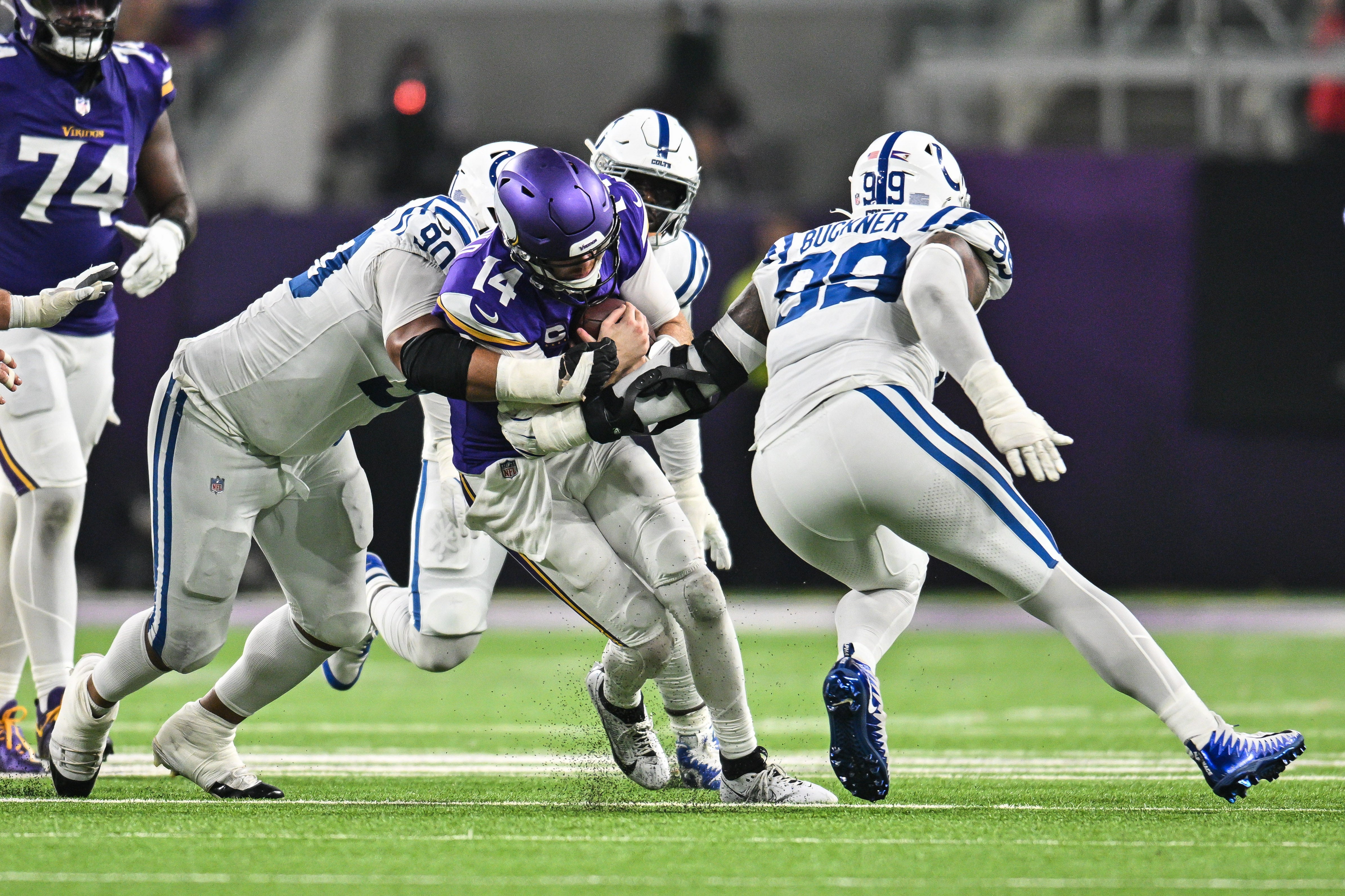 Nov 3, 2024; Minneapolis, Minnesota, USA; Minnesota Vikings quarterback Sam Darnold (14) is tackled by Indianapolis Colts defensive tackle Grover Stewart (90) and defensive tackle DeForest Buckner (99) during the second quarter at U.S. Bank Stadium.
