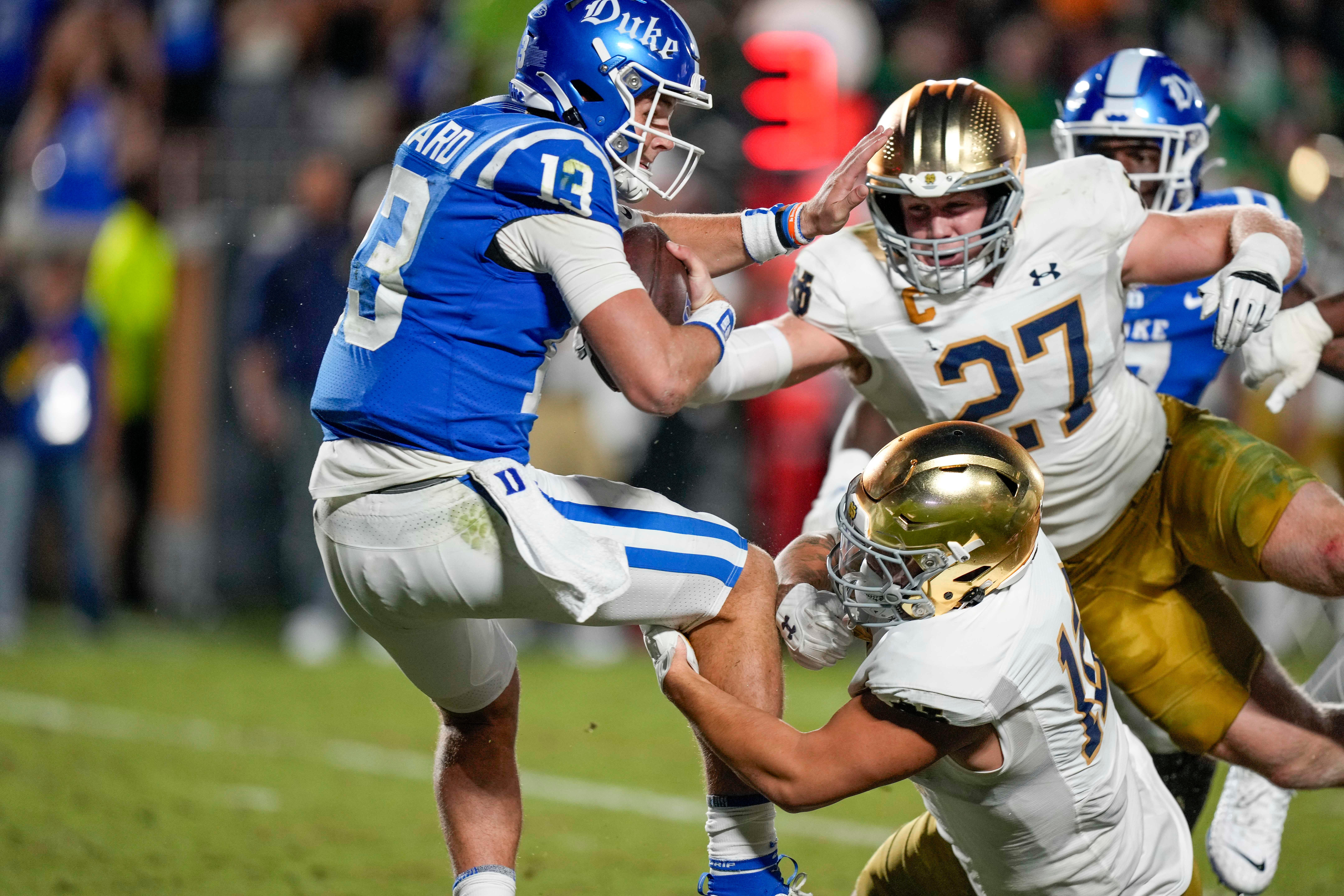 Duke Blue Devils quarterback Riley Leonard (13) is sacked by Notre Dame Fighting Irish defensive lineman Jordan Botelho (12) and linebacker JD Bertrand (27) during the second quarter at Wallace Wade Stadium.