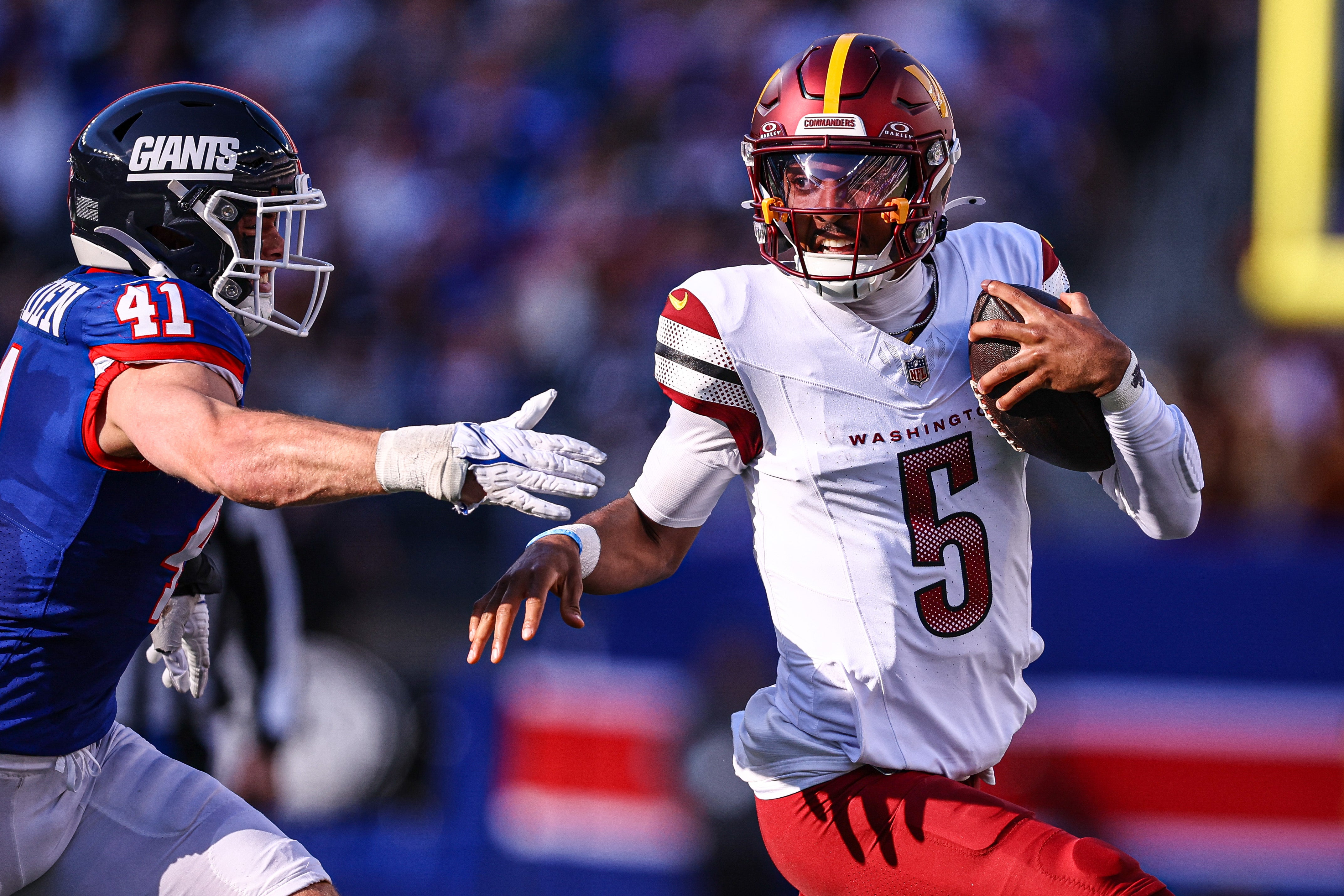 Nov 3, 2024; East Rutherford, New Jersey, USA; Washington Commanders quarterback Jayden Daniels (5) scrambles away from New York Giants linebacker Micah McFadden (41) during the first half at MetLife Stadium.