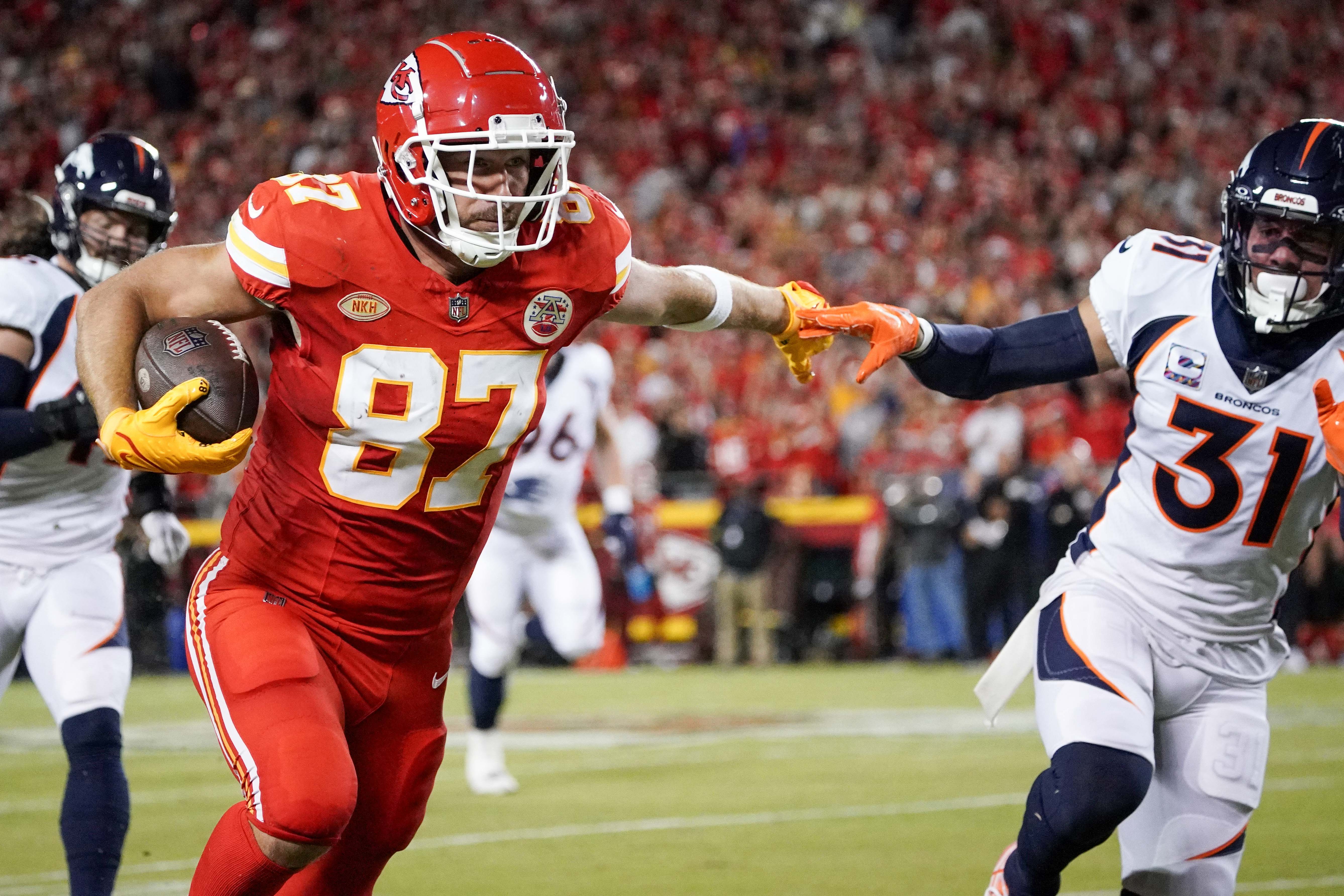 Chiefs tight end Travis Kelce (87) runs the ball as Denver Broncos safety Justin Simmons (31) defends.