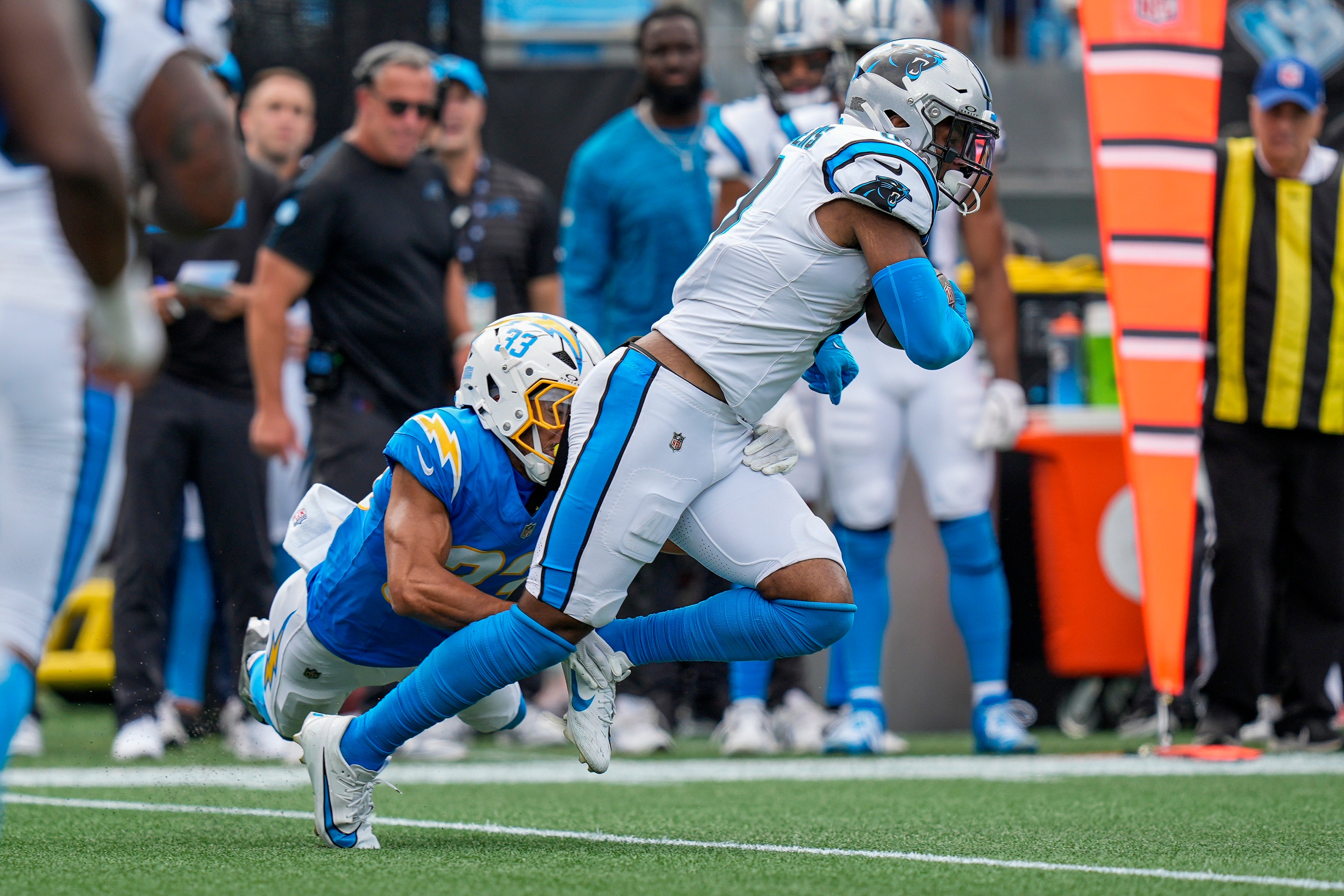 Sep 15, 2024; Charlotte, North Carolina, USA; Los Angeles Chargers cornerback Deane Leonard (33) tackles Carolina Panthers running back Miles Sanders (6) during the second half at Bank of America Stadium.