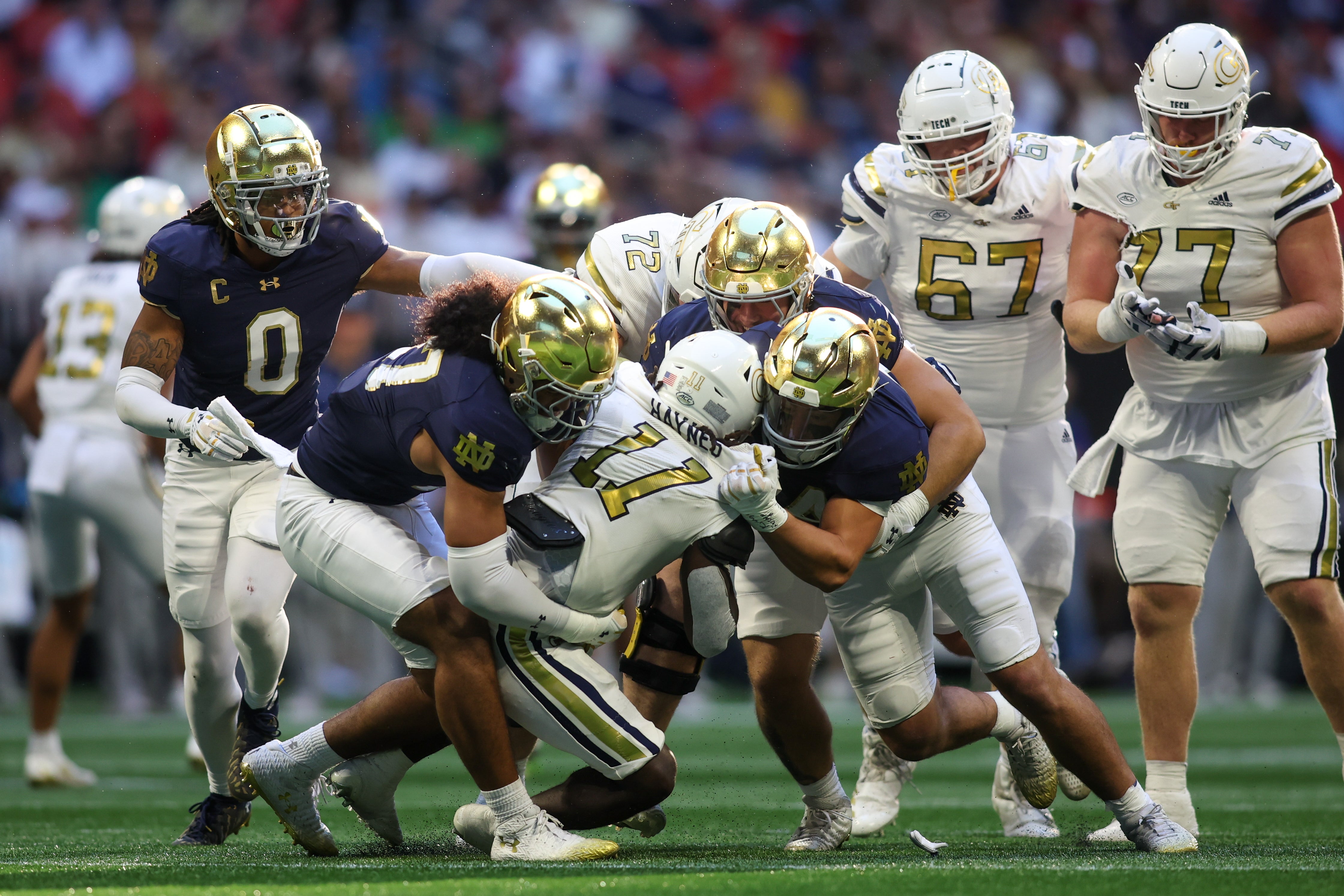 Georgia Tech Yellow Jackets running back Jamal Haynes (11) is tackled by Notre Dame Fighting Irish linebacker Kyngstonn Viliamu-Asa (27) and defensive lineman Donovan Hinish (41) and linebacker Drayk Bowen (34) in the third quarter at Mercedes-Benz Stadium.