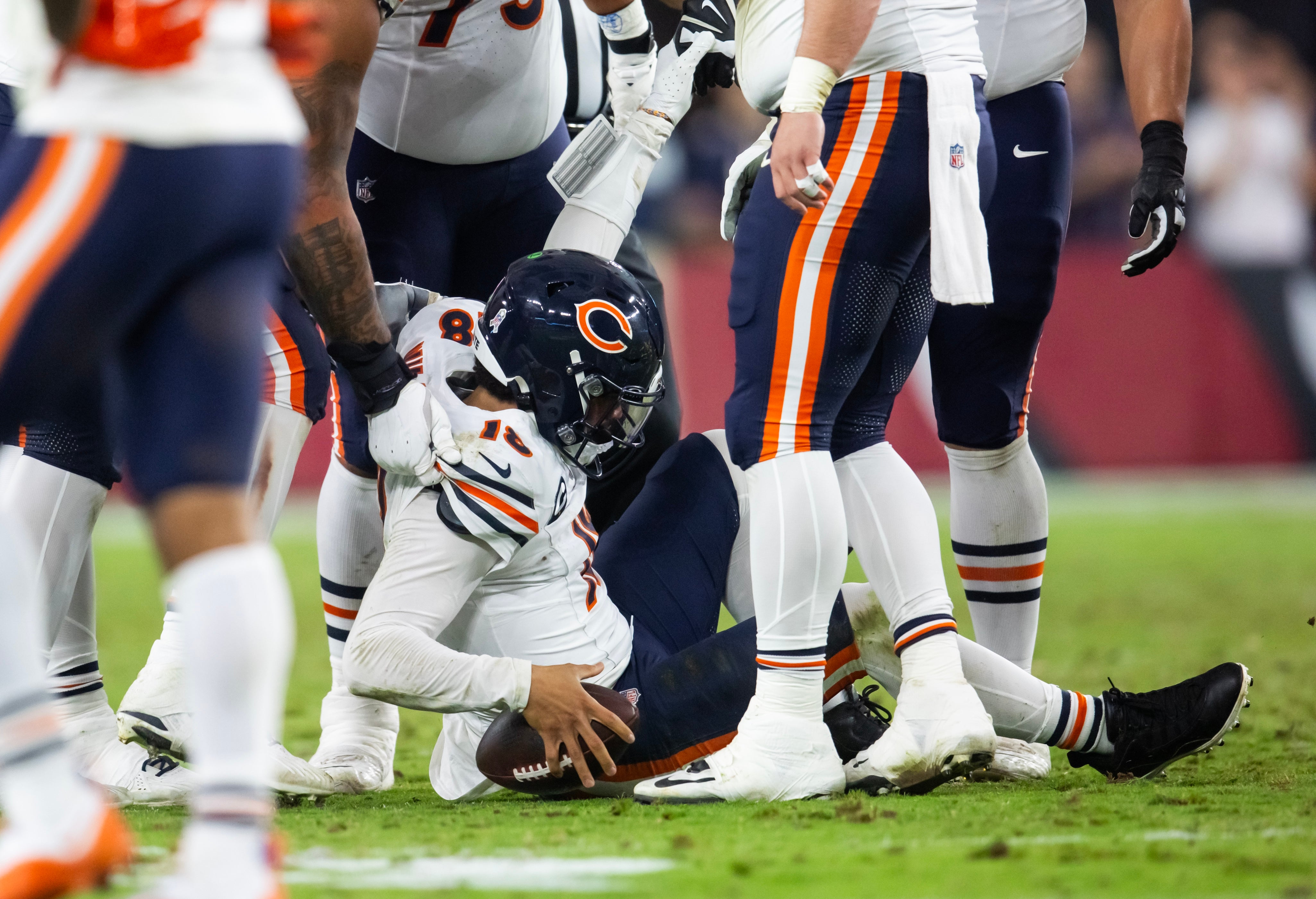 Nov 3, 2024; Glendale, Arizona, USA; Chicago Bears quarterback Caleb Williams (18) is helped up by teammates after being sacked by the Arizona Cardinals at State Farm Stadium.