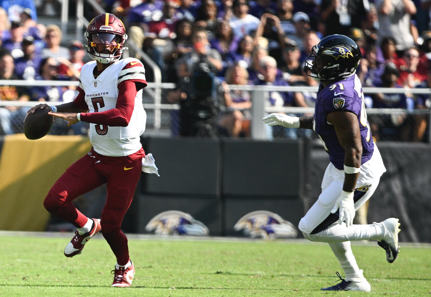 Oct 13, 2024; Baltimore, Maryland, USA; Washington Commanders quarterback Jayden Daniels (5) looks to throw on the run as Baltimore Ravens defensive end Yannick Ngakoue (91) applies pressure during the second half at M&T Bank Stadium.
