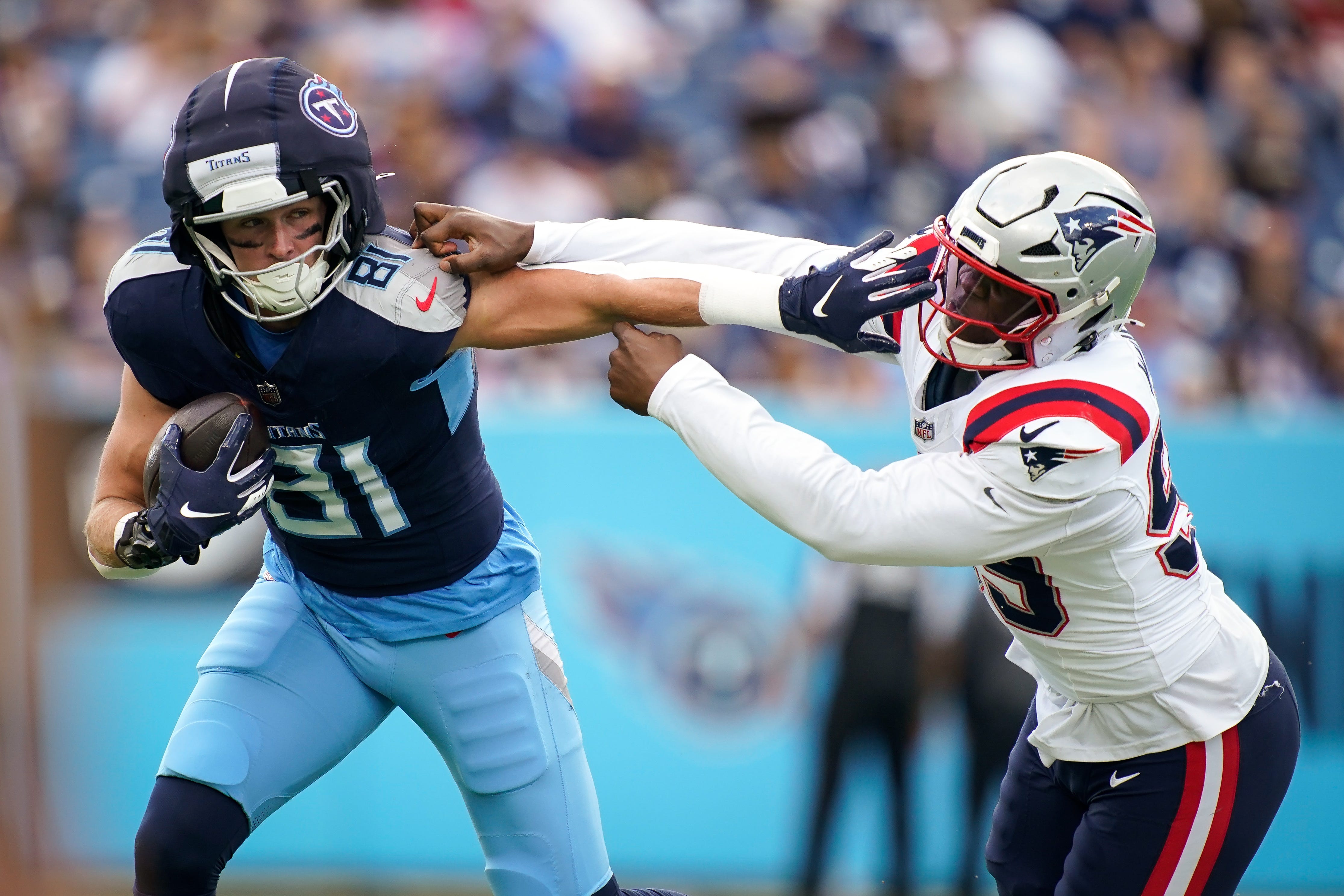 Tennessee Titans tight end Josh Whyle (81) stiff arms New England Patriots defensive end Keion White (99) bringing in a first down during the first quarter at Nissan Stadium in Nashville, Tenn., Sunday, Nov. 3, 2024.