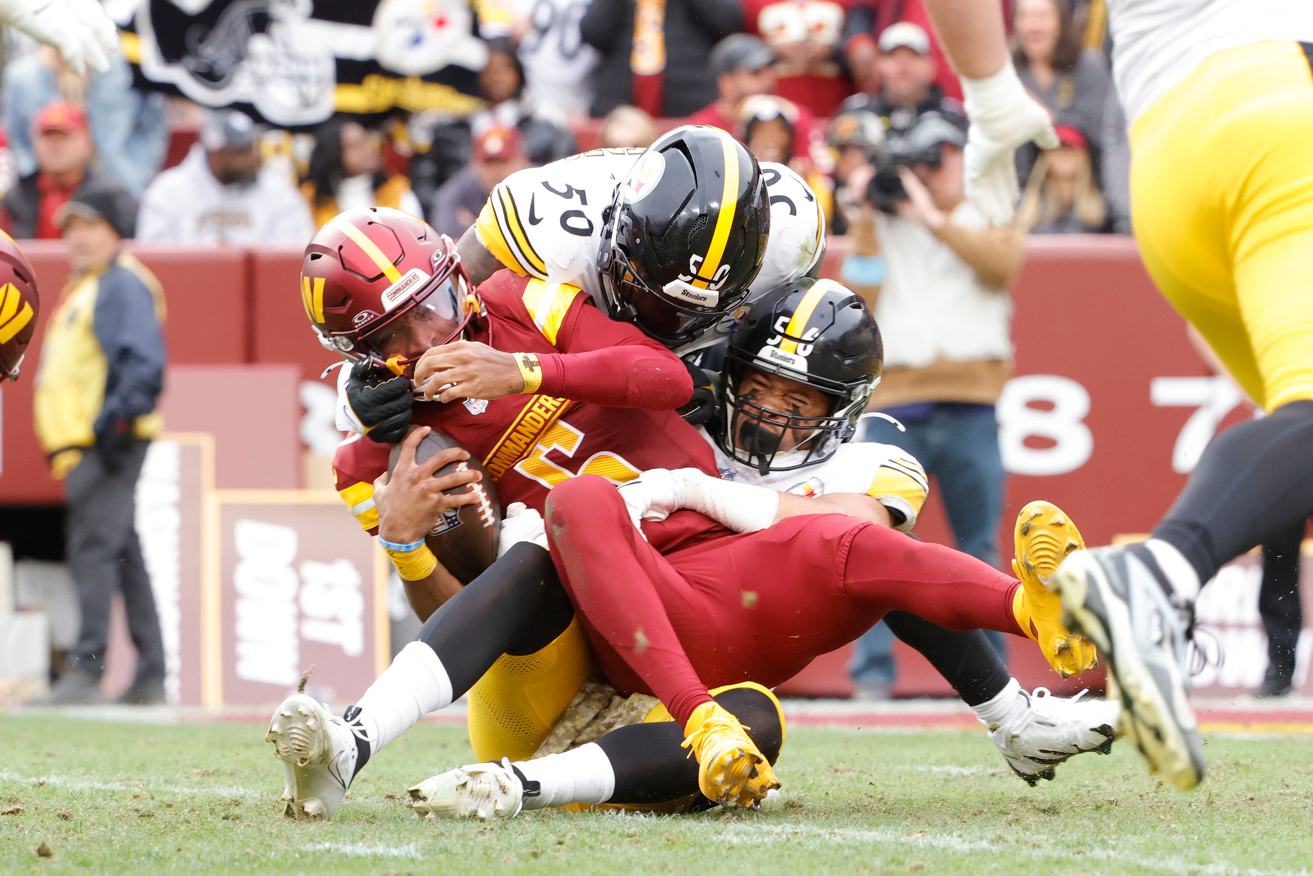 Nov 10, 2024; Landover, Maryland, USA; Washington Commanders quarterback Jayden Daniels (5) is sacked by Pittsburgh Steelers linebacker Elandon Roberts (50) and Steelers linebacker Alex Highsmith (56) during the first half at Northwest Stadium.