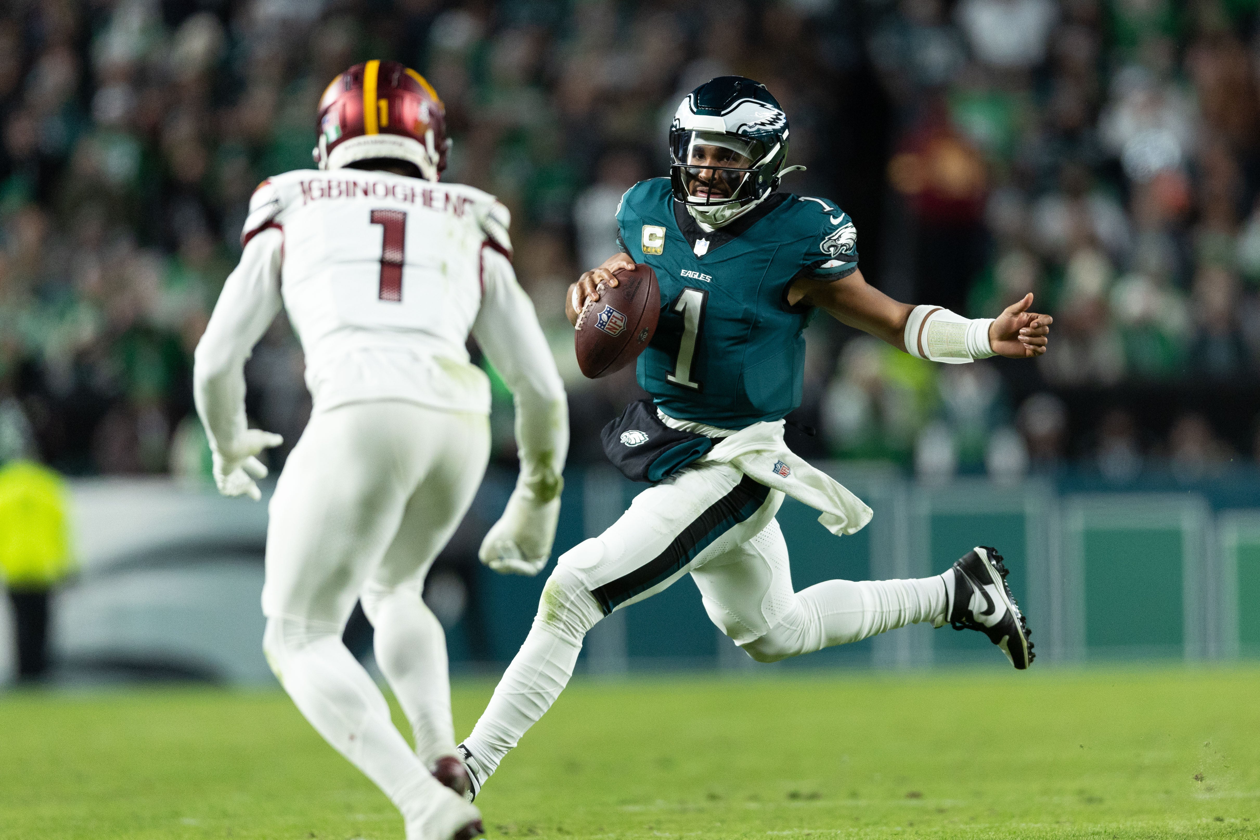 Philadelphia Eagles quarterback Jalen Hurts (1) runs with the ball in front of Washington Commanders cornerback Noah Igbinoghene (1) during the second quarter at Lincoln Financial Field.