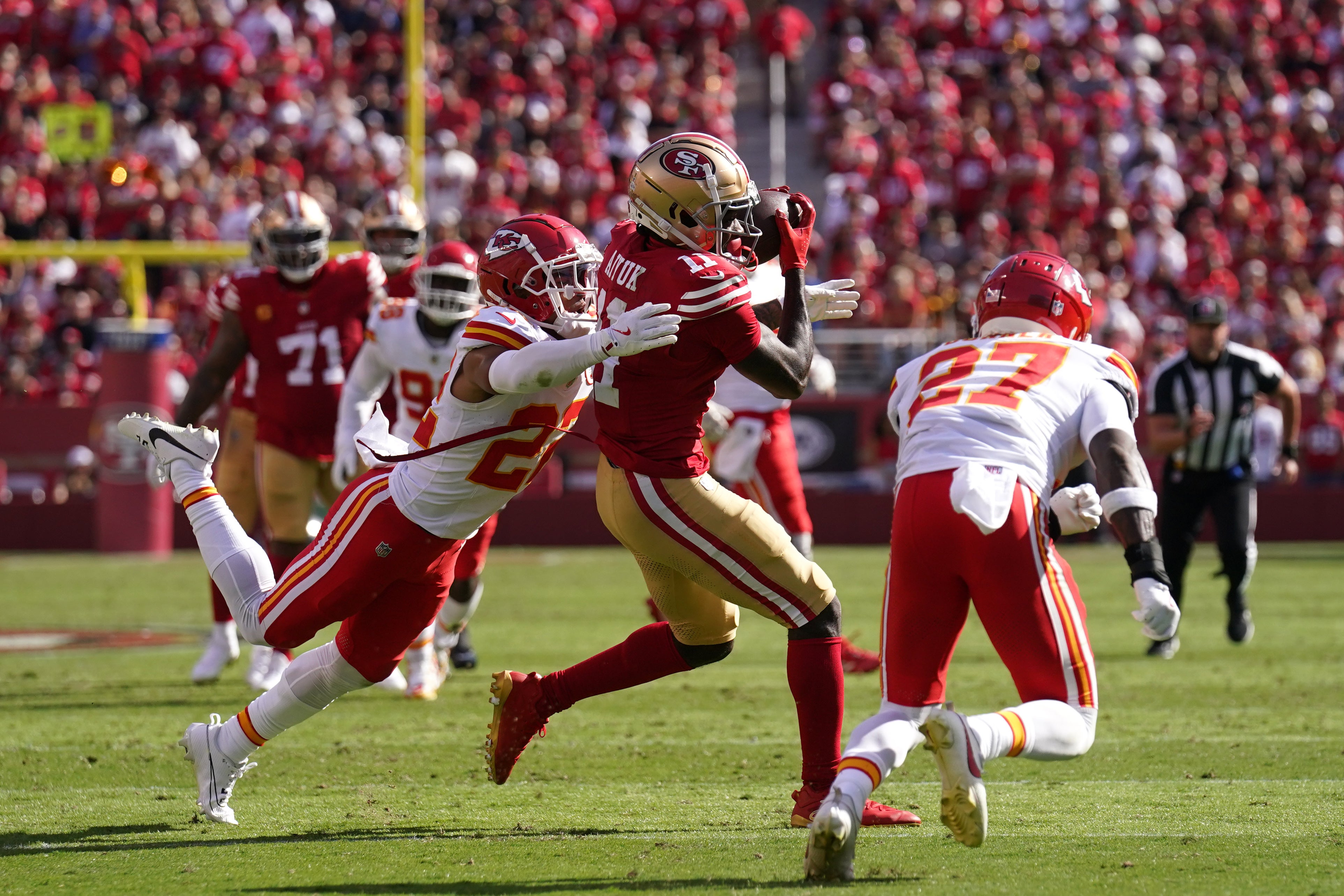 San Francisco 49ers wide receiver Brandon Aiyuk (11) catches a pass between Kansas City Chiefs cornerback Trent McDuffie (22) and safety Chamarri Conner (27) in the second quarter at Levi's Stadium.