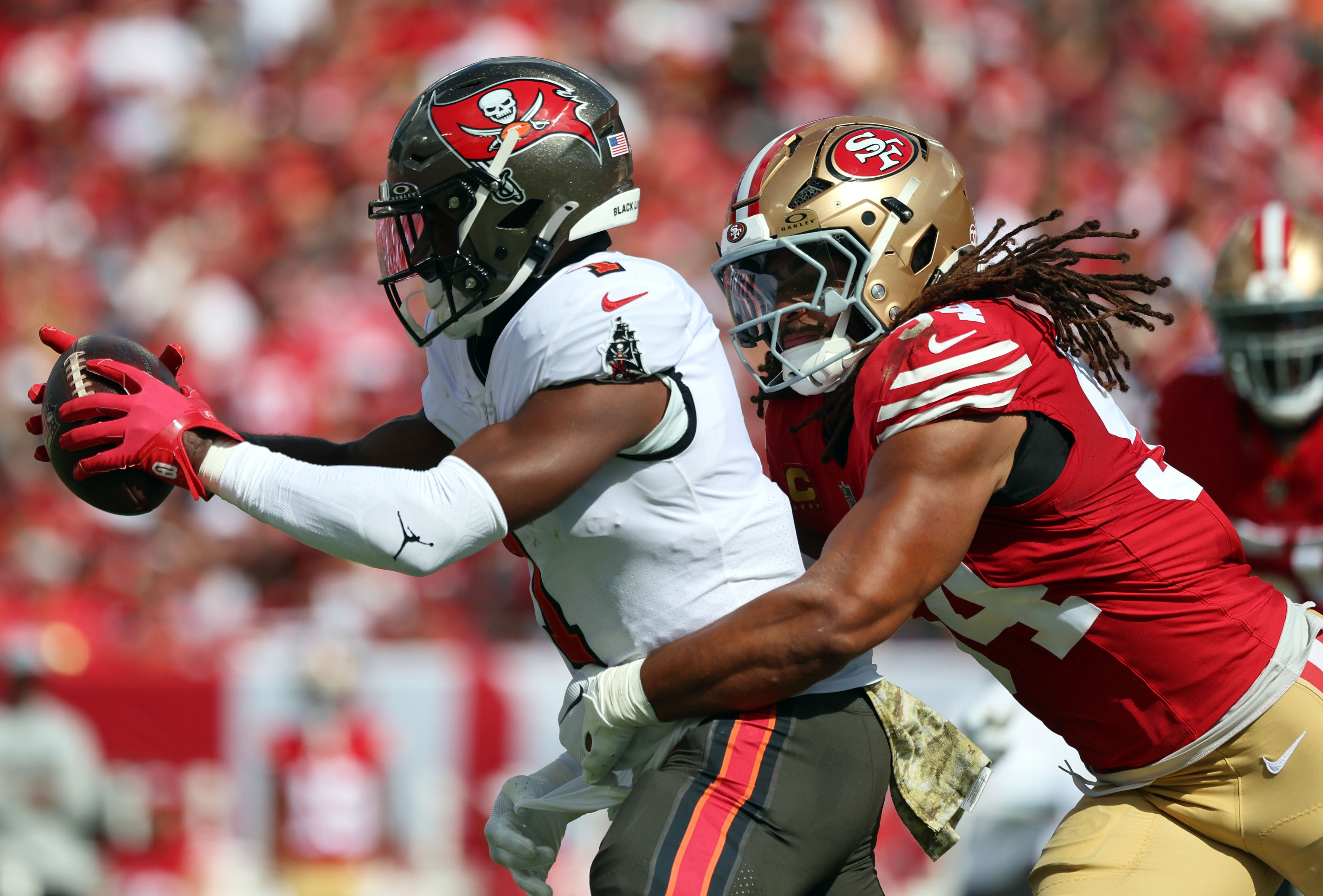 Tampa Bay Buccaneers running back Rachaad White (1) runs with the ball as San Francisco 49ers linebacker Fred Warner (54) tackles during the first half at Raymond James Stadium.