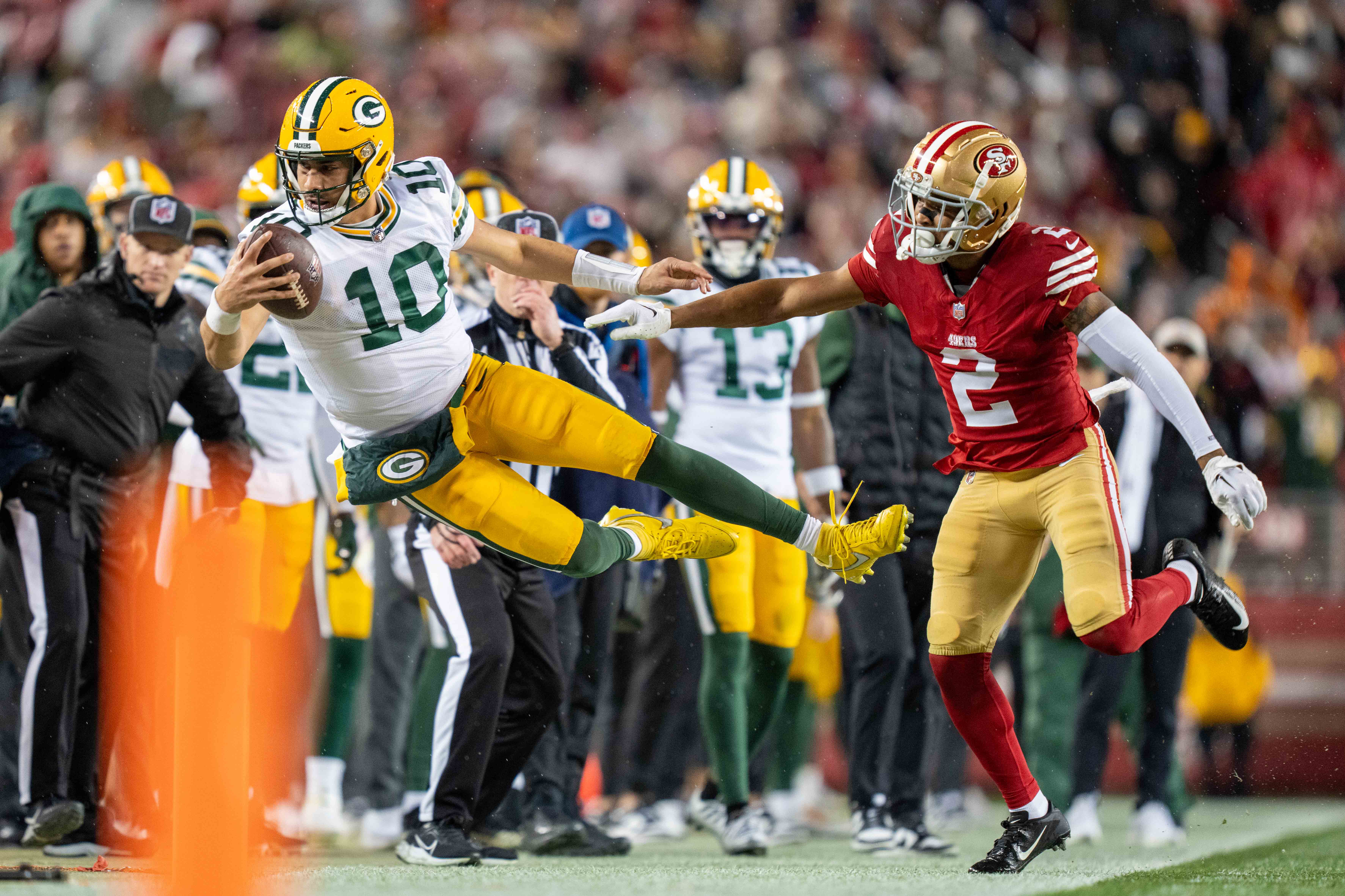 Green Bay Packers quarterback Jordan Love (10) is pushed out of bounds by San Francisco 49ers cornerback Deommodore Lenoir (2) during the second quarter in a 2024 NFC divisional round game at Levi's Stadium.