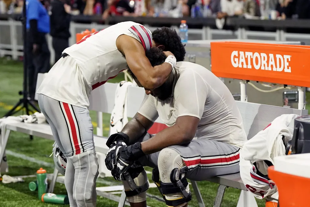 Ohio State Buckeyes offensive lineman Dawand Jones (right) is consoled after losing the 2022 Peach Bowl against the Georgia Bulldogs at Mercedes-Benz Stadium.