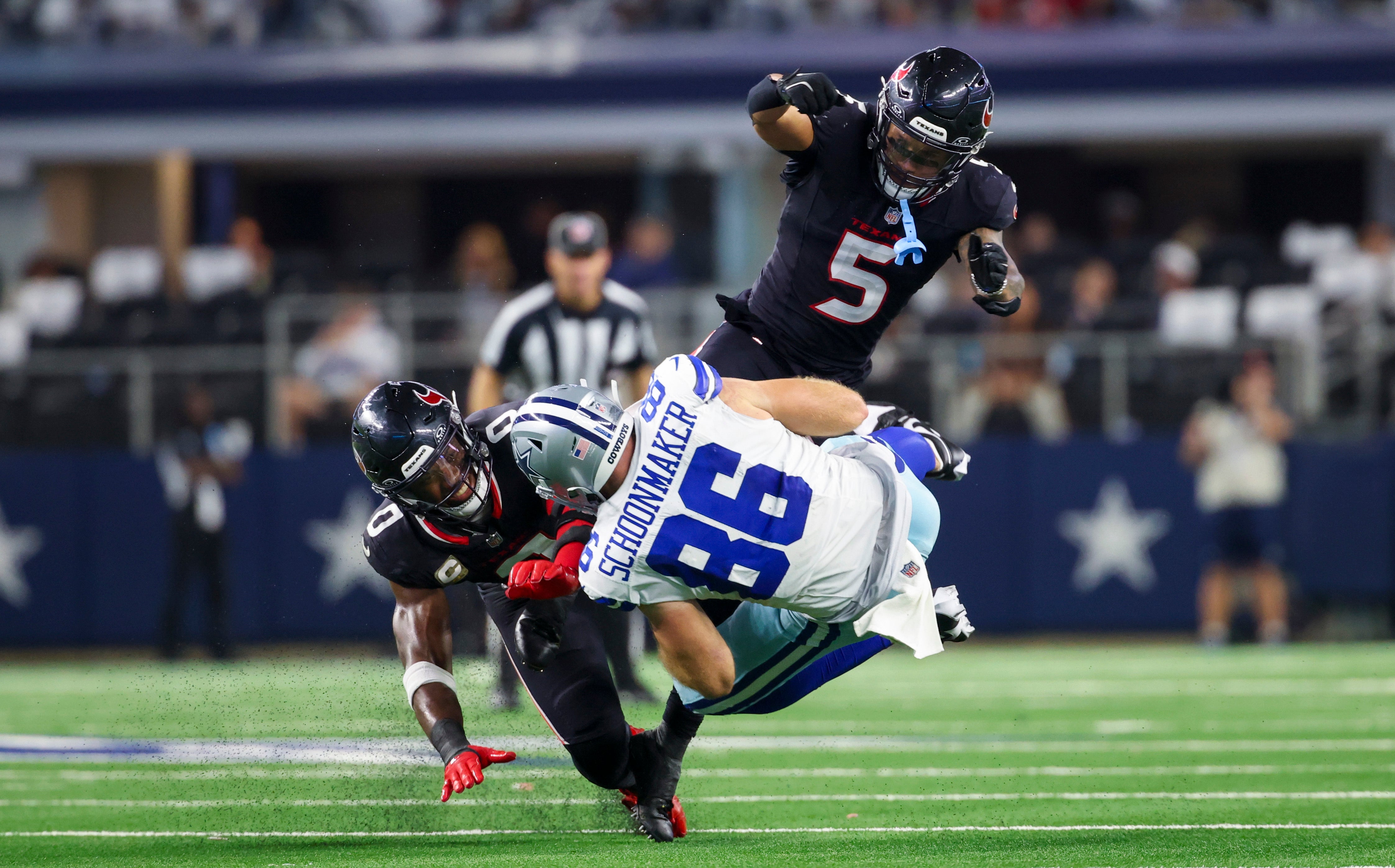 Houston Texans linebacker Azeez Al-Shaair (0) and Houston Texans safety Jalen Pitre (5) tackle Dallas Cowboys tight end Luke Schoonmaker (86) during the second half at AT&T Stadium.