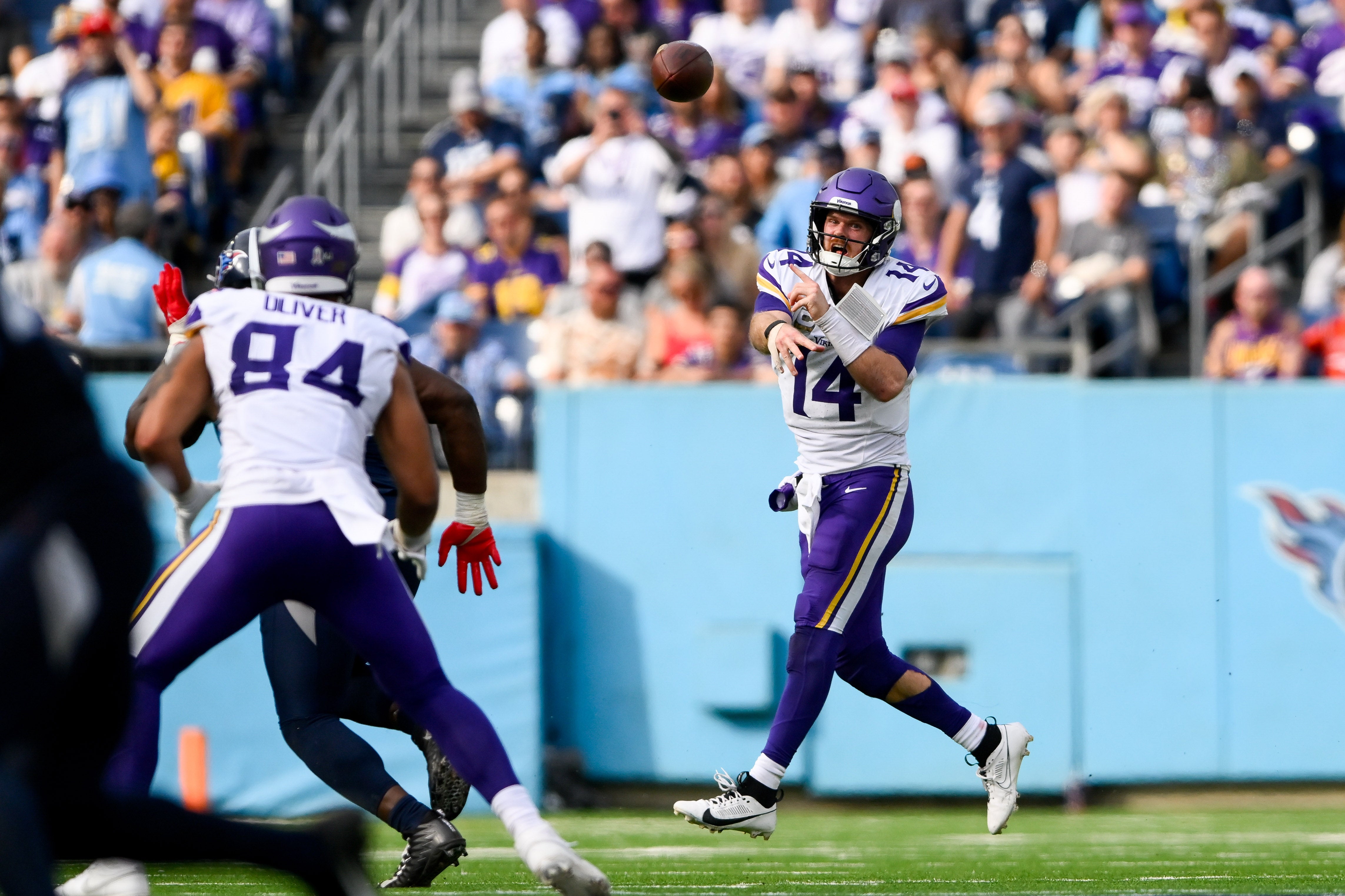 Nov 17, 2024; Nashville, Tennessee, USA; Minnesota Vikings quarterback Sam Darnold (14) rolls out and throws a pass to tight end Josh Oliver (84) against the Tennessee Titans during the first half at Nissan Stadium.