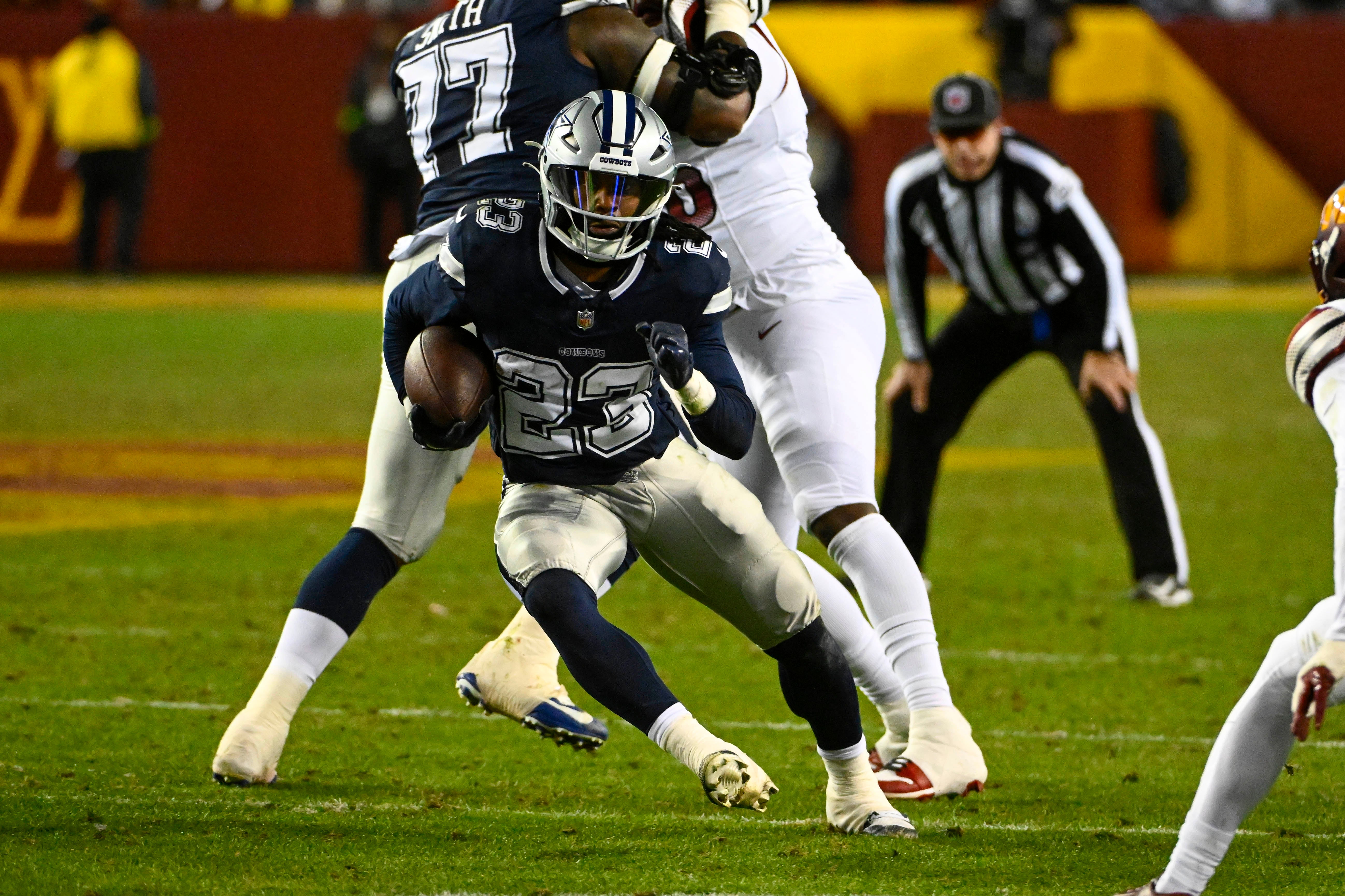Dallas Cowboys running back Rico Dowdle (23) carries the ball past Washington Commanders safety Terrell Burgess (32) during the second half at FedExField.