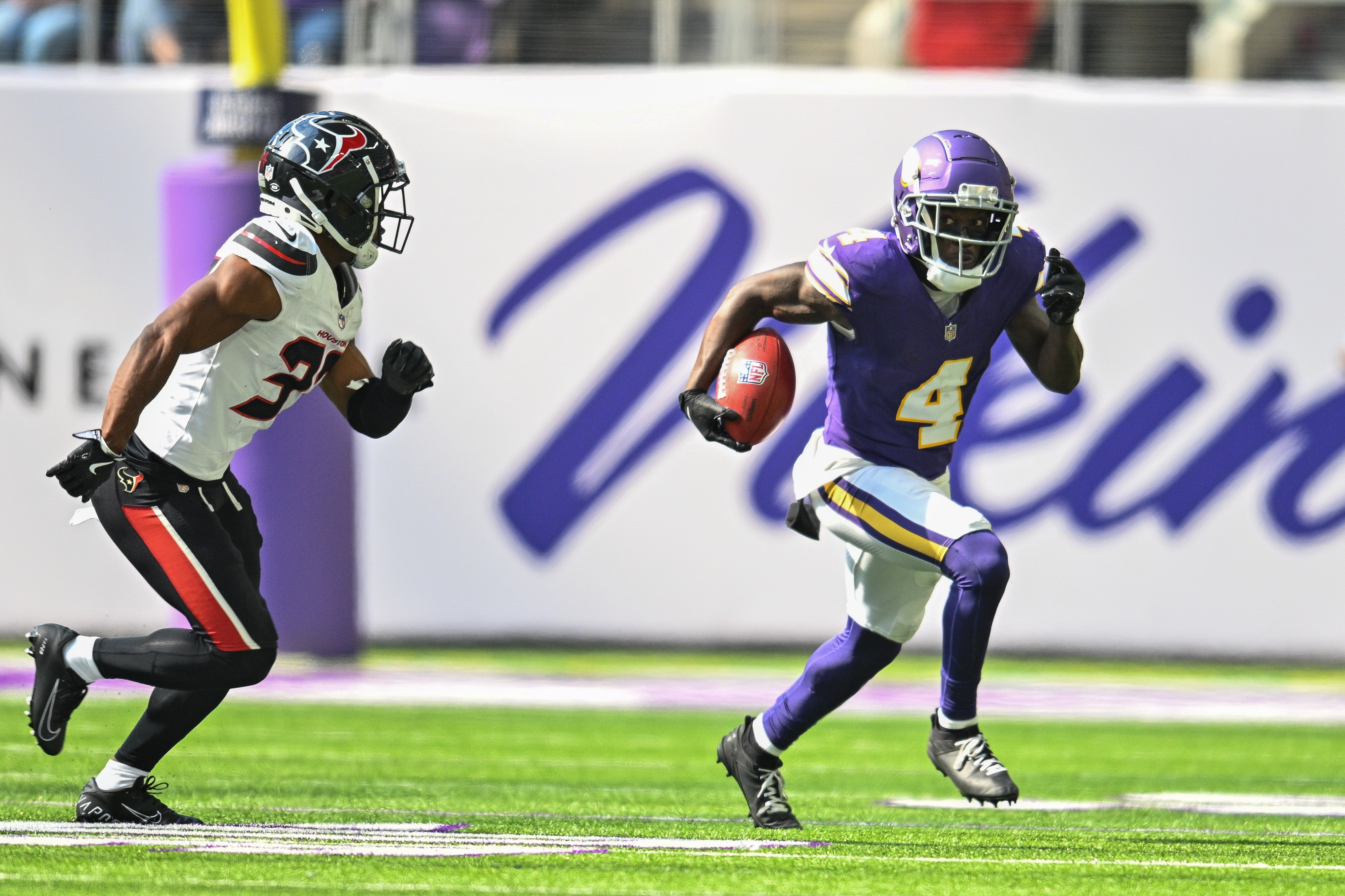 Sep 22, 2024; Minneapolis, Minnesota, USA; Minnesota Vikings wide receiver Brandon Powell (4) runs the ball as defends Houston Texans cornerback D'Angelo Ross (37) pursues during the fourth quarter at U.S. Bank Stadium.