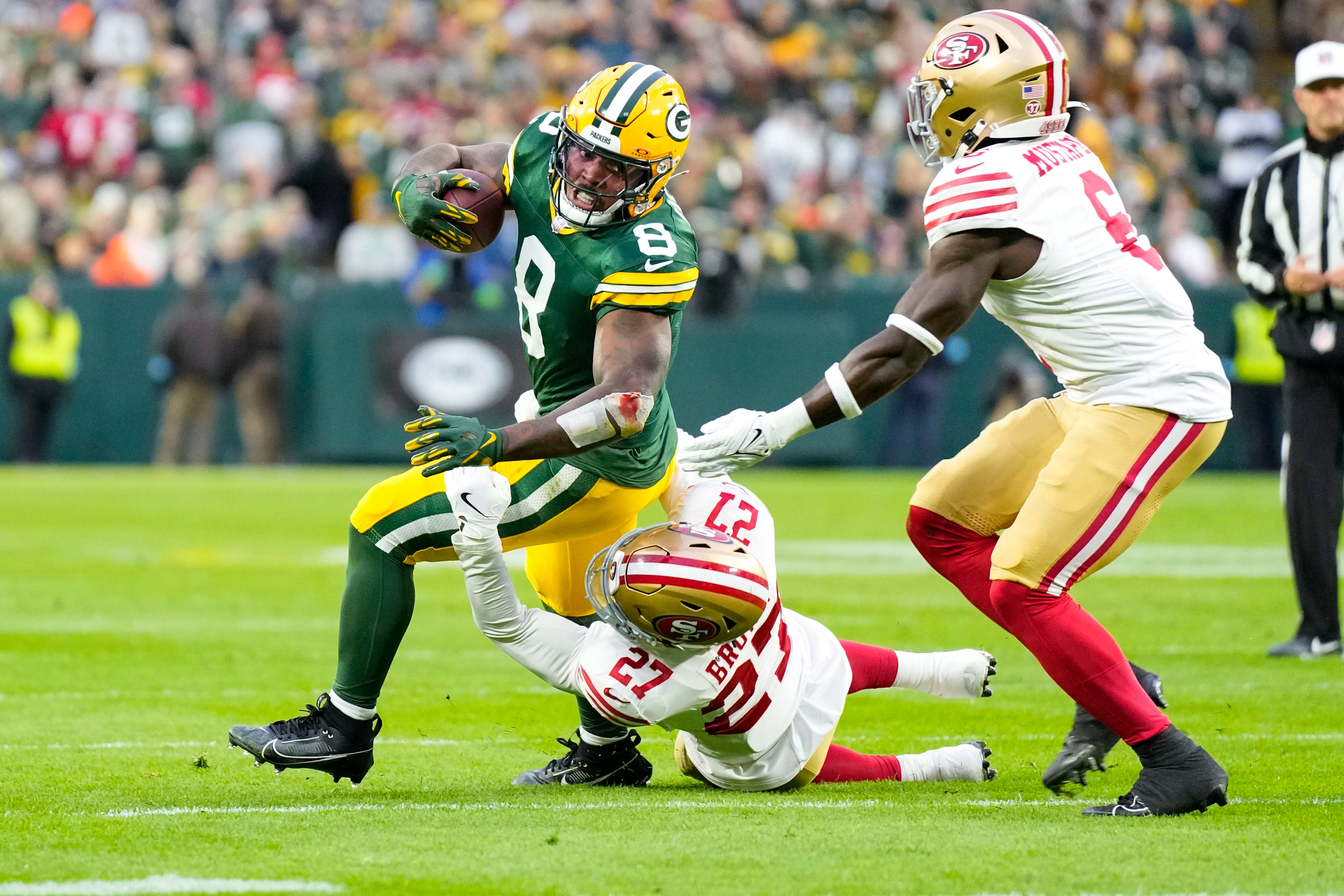 Green Bay Packers running back Josh Jacobs (8) is tackled by San Francisco 49ers safety Ji'Ayir Brown (27) during the first quarter at Lambeau Field.