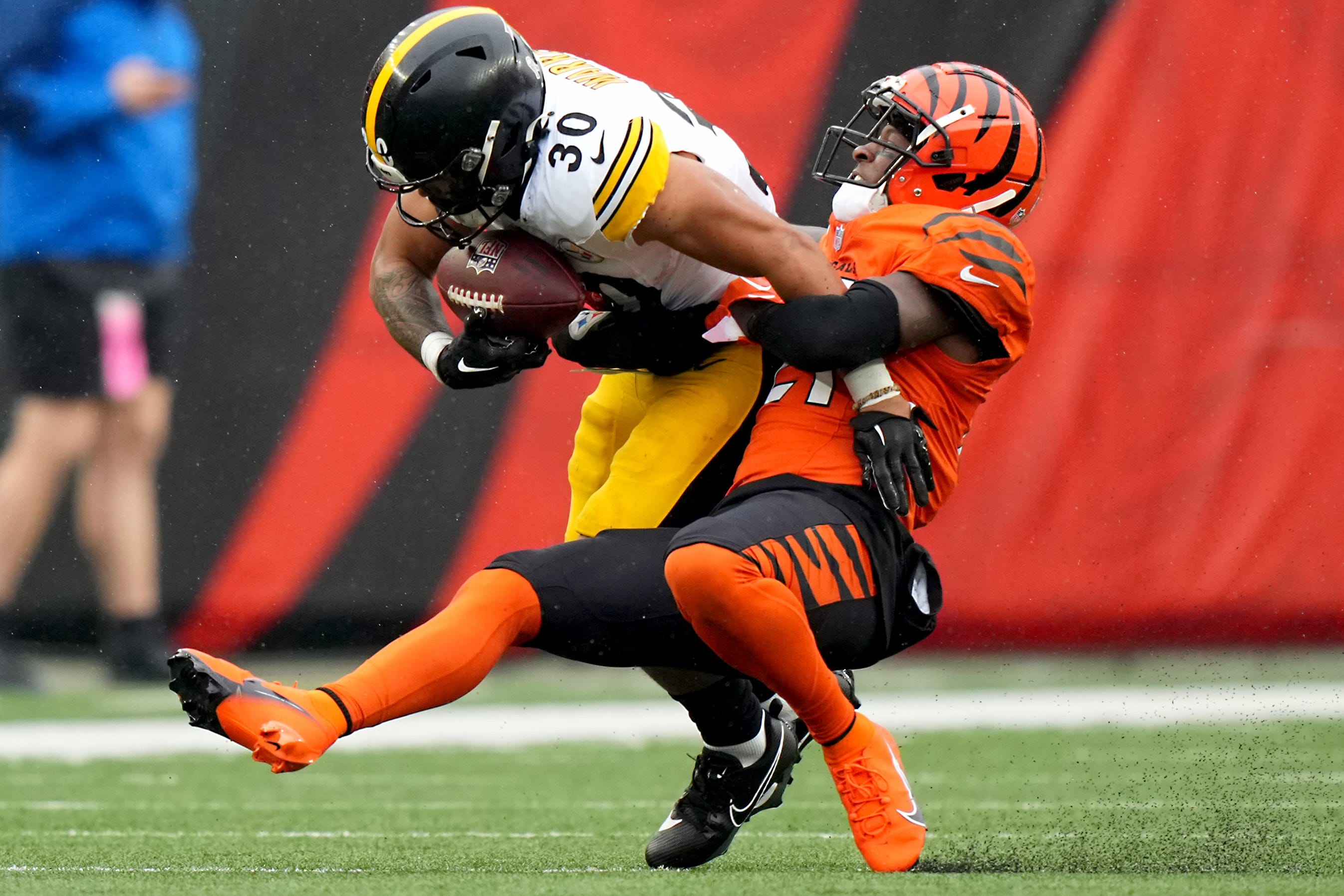 Cincinnati Bengals cornerback Mike Hilton (21) tackles Pittsburgh Steelers running back Jaylen Warren (30) in the first quarter of a Week 12 NFL football game between the Pittsburgh Steelers and the Cincinnati Bengals, Sunday, Nov. 26, 2023, at Paycor Stadium.  
