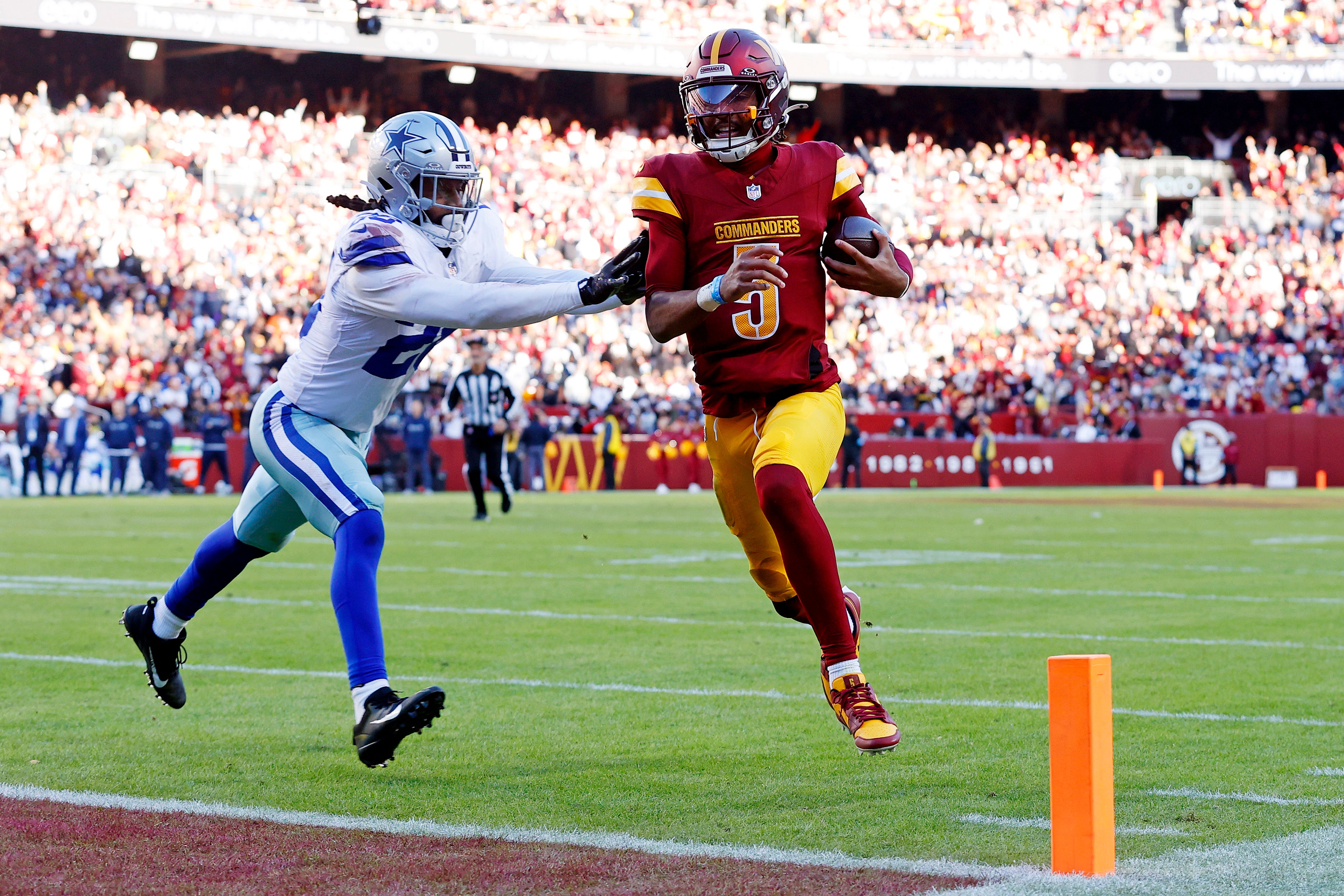 Nov 24, 2024; Landover, Maryland, USA; Washington Commanders quarterback Jayden Daniels (5) runs for a touchdown against Dallas Cowboys safety Malik Hooker (28) during the third quarter at Northwest Stadium.