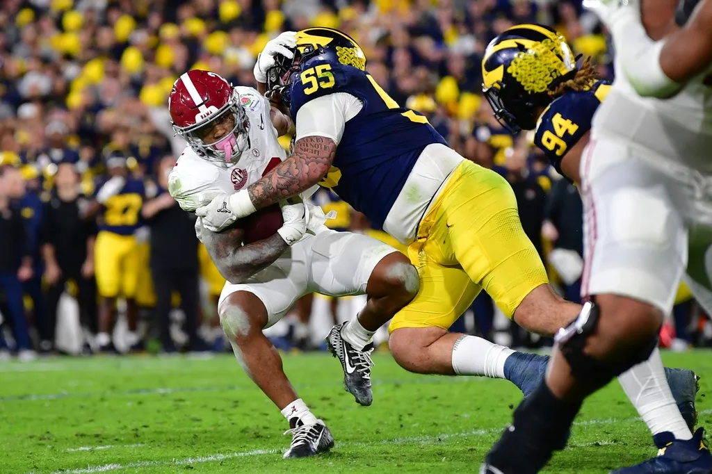 Michigan Wolverines defensive lineman Mason Graham (55) tackles Alabama Crimson Tide running back Jase McClellan (2) during overtime in the 2024 Rose Bowl college football playoff semifinal game.