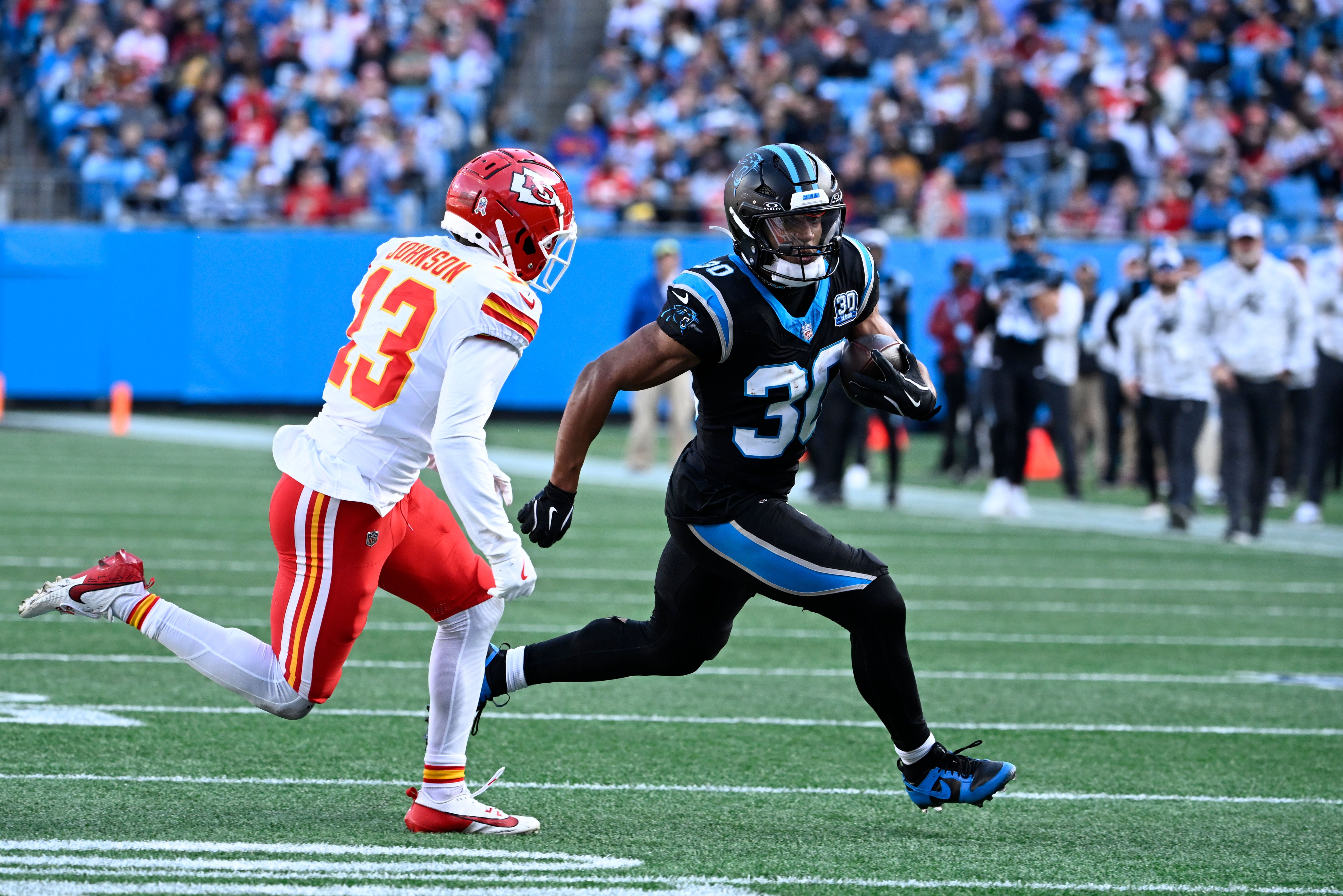 Panthers running back Chuba Hubbard (30) runs as Chiefs cornerback Nazeeh Johnson (13) defends.